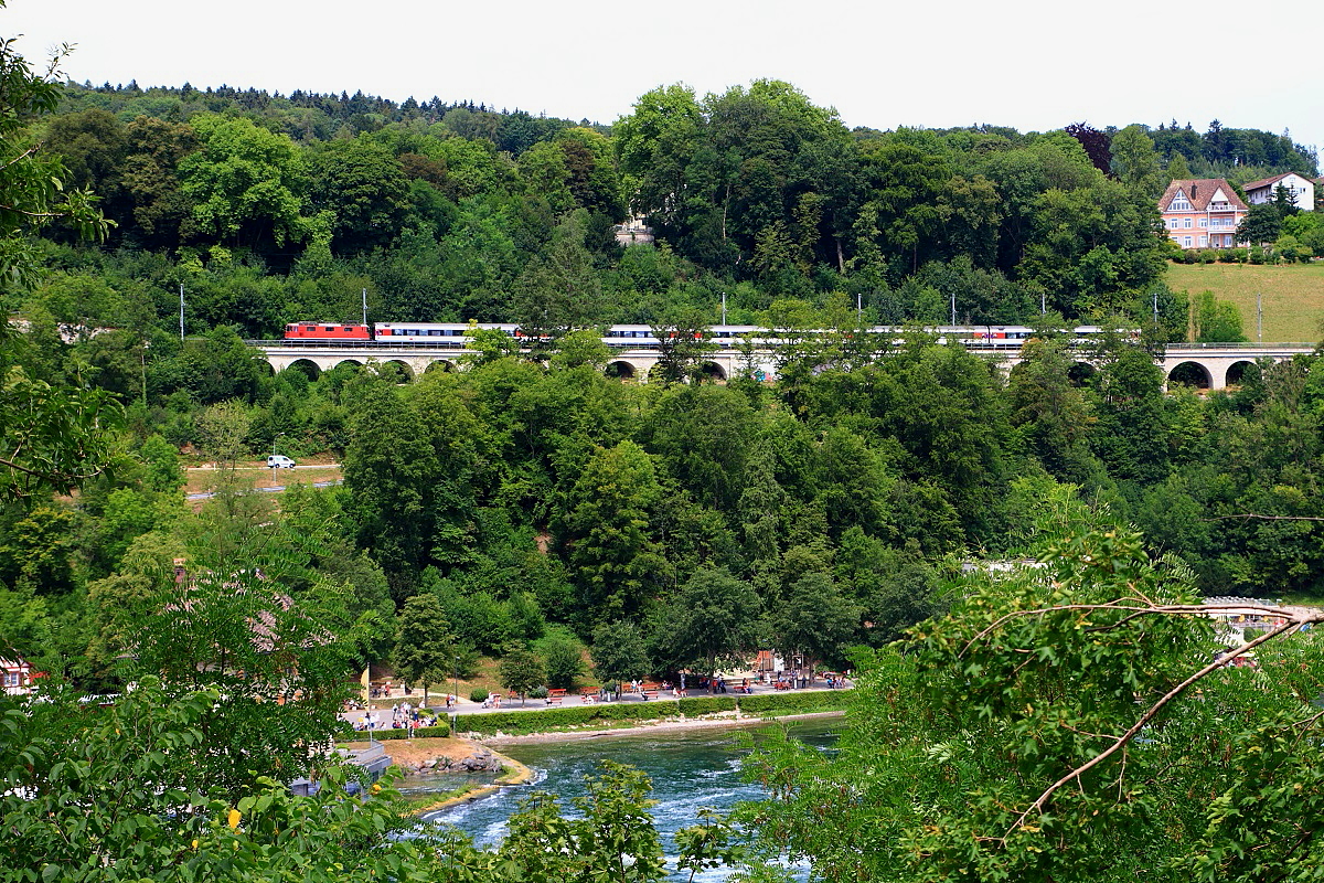 Mit einem EC nach Zrich ist eine Re 4/4 II am 26.07.2015 oberhalb des Rheinfalls unterwegs, die Aufnahme entstand vom Bahnsteig des Haltepunktes Schloss Laufen aus