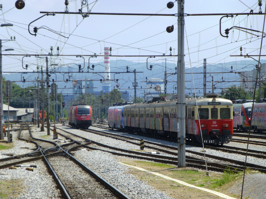 Eine Garnitur 315er Triebwagen steht im hinteren Teil des Hauptbahnhofes von Ljubljana. Der Verkehr auf den elektrifizierten Strecken wird heute vor allem von den Baureihen 312-0 und 312-1 abgewickelt, die dort auch stehen.Auerdem zu erkennen sind zwei Mehrsystemloks des Typs Taurus.