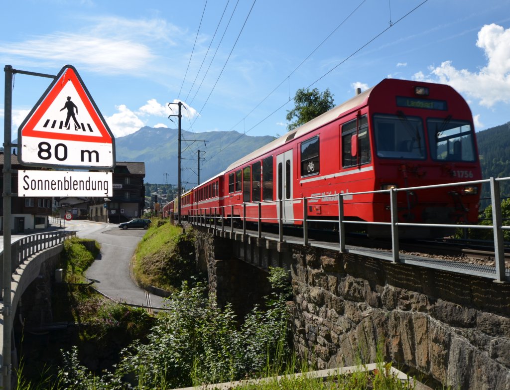 Zug von Scuol-Tarasp nach Landquart kurz hinter dem Bahnhof Klosters Dorf.
Das linke Schild warnt offensichtlich vor tiefstehender Morgensonne (von links hinten). Der besondere Effekt ist aber offensichtlich durch den Blitz hervorgerufen.
(Aufnahme 10.08.2012)