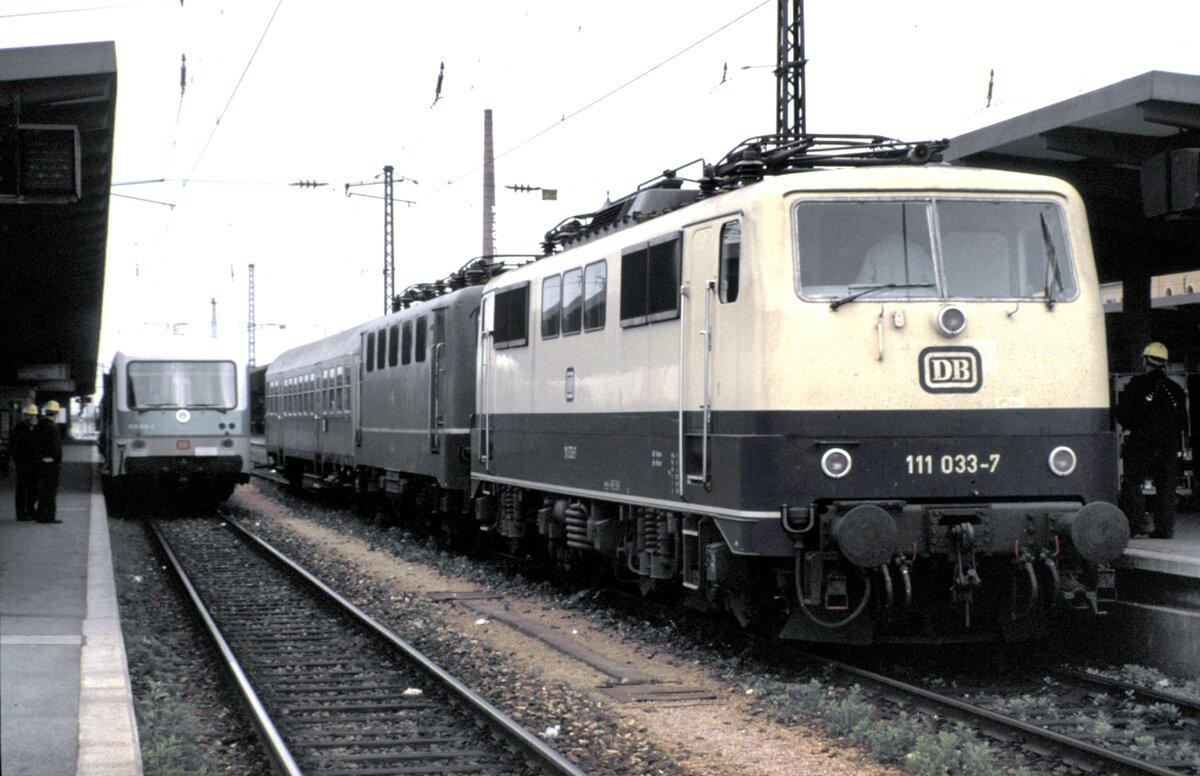 111 033-7 mit einer 141 im Schlepp und einem Silberling; auf dem Nachbargleis 628 313-9 in Augsburg Hbf am 15.05.1988.