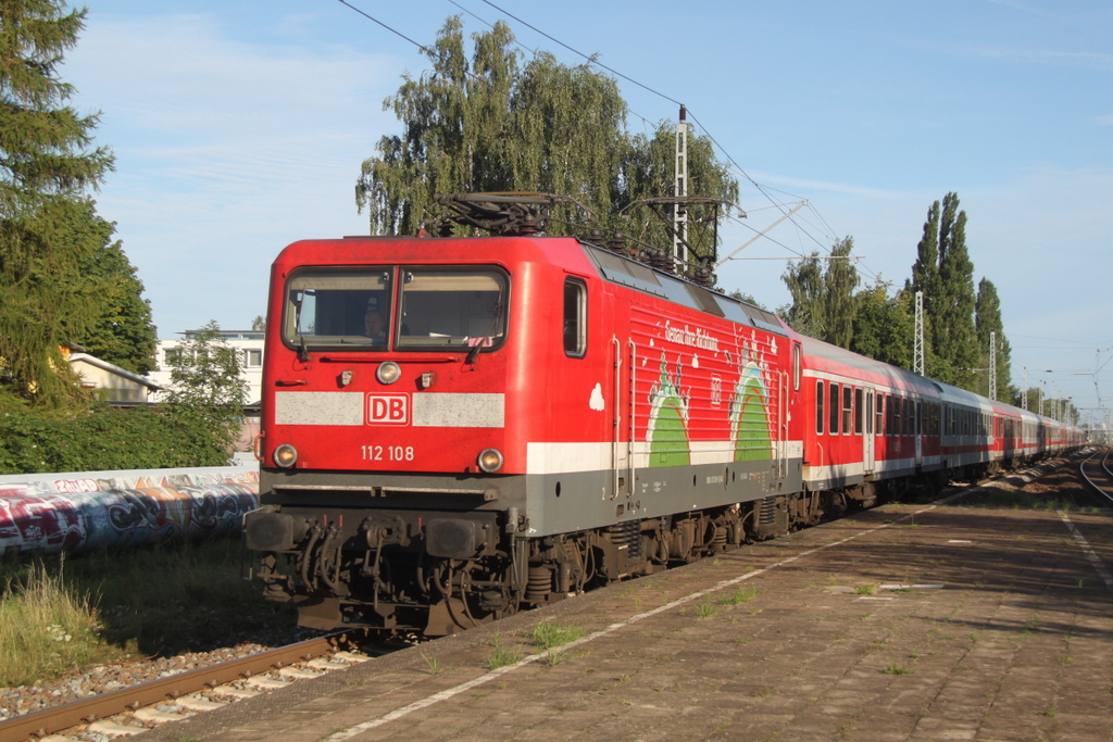 112 108-6( Genau Ihre Richtung ) mit dem Pommes Rot-Wei� Express 13290 von Warnem�nde nach Berlin-Ostbahnhof bei der Durchfahrt am 29.08.2015 im Haltepunkt Rostock-Holbeinplatz