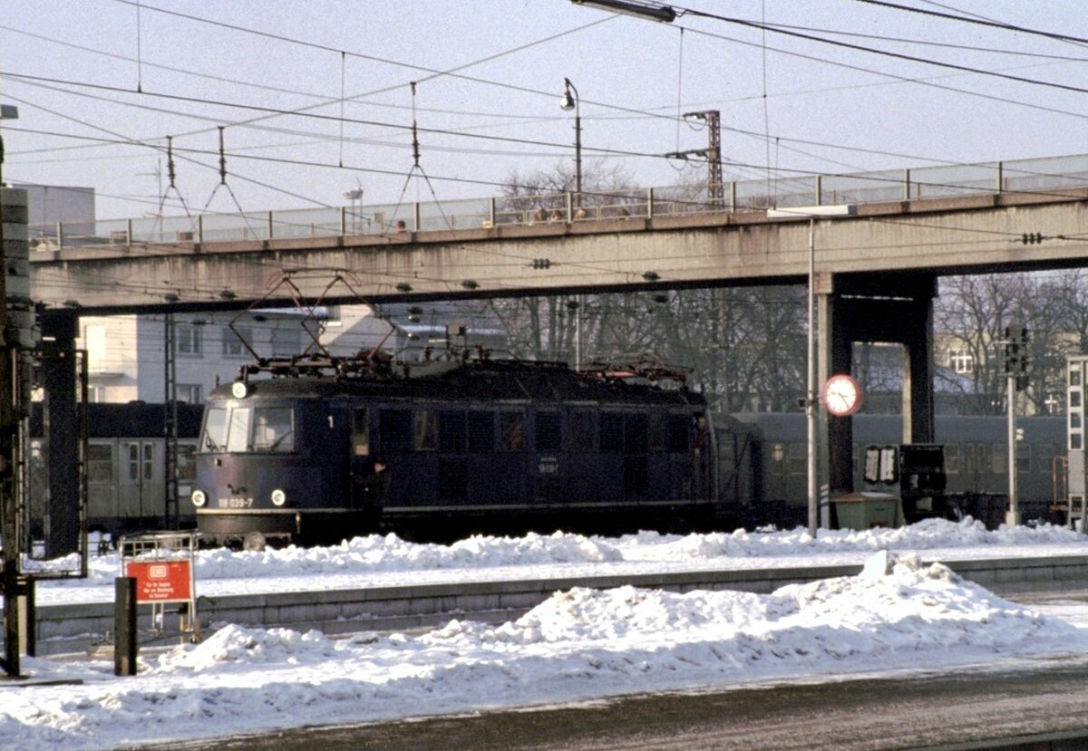 118 039-7 rangiert in Ulm am 30.01.1987 - an der Führerstandstür 1 hält sich der Rangierer fest, der Lokführer schaut aus Führerstandstür 2.