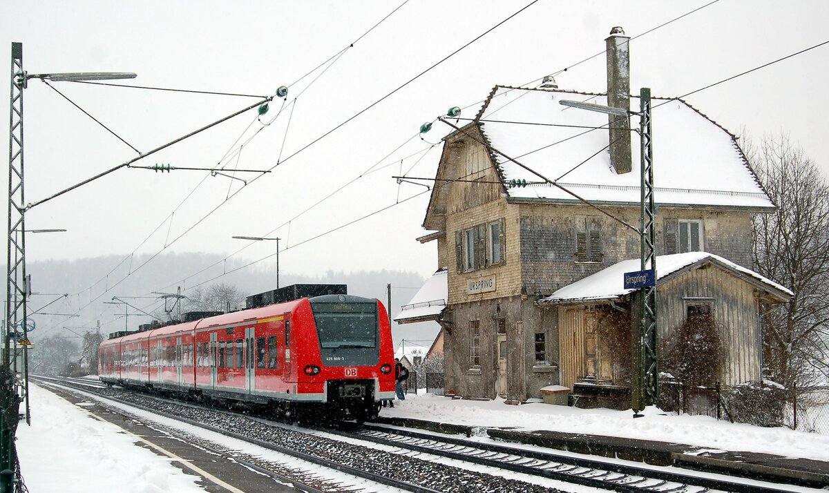 425 808-3 in Urspring am 13.02.2009. Der Bahnhof steht kurz vor dem Abbruch. Das architektonisch interessante Gebäude hat man derart verkommen lassen dass nichts zu retten war. Erhalten geblieben ist nur der Holzkasten mit dem Erdungskabel am Masten mit dem Ortsnamen Urspring.