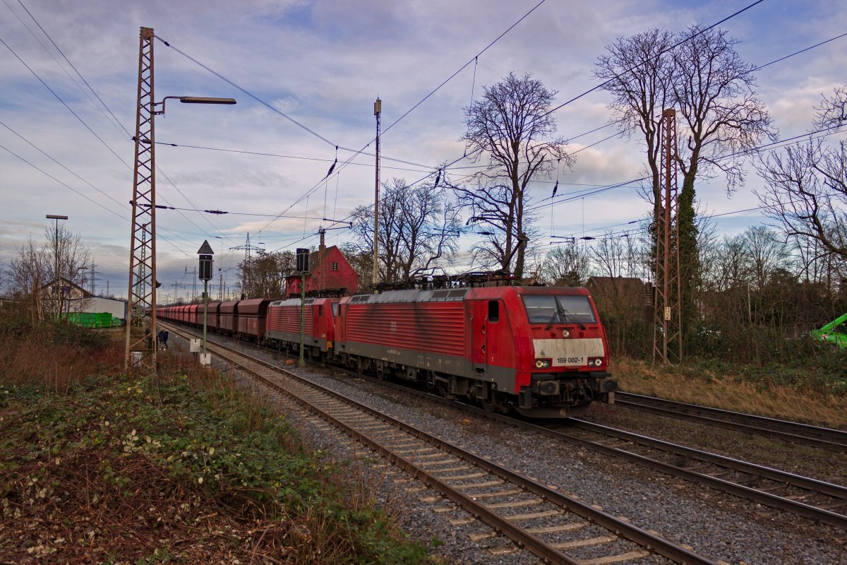 Am s�dlichen Ende des Bahnhofes Lintorf hat dieser von 189 082 und 189 046 bef�rderte Erzzug soeben die Ausfahrsignale in Richtung D�sseldorf passiert. Der Zug ist aus sechsachsigen Falrrs-Wagen gebildet, die wegen der extrem hohen Zuggewichte �ber Mittelpufferkupplungen verf�gen. Interessanterweise hat die f�hrende 189 082 jedoch keine solche Kupplung.