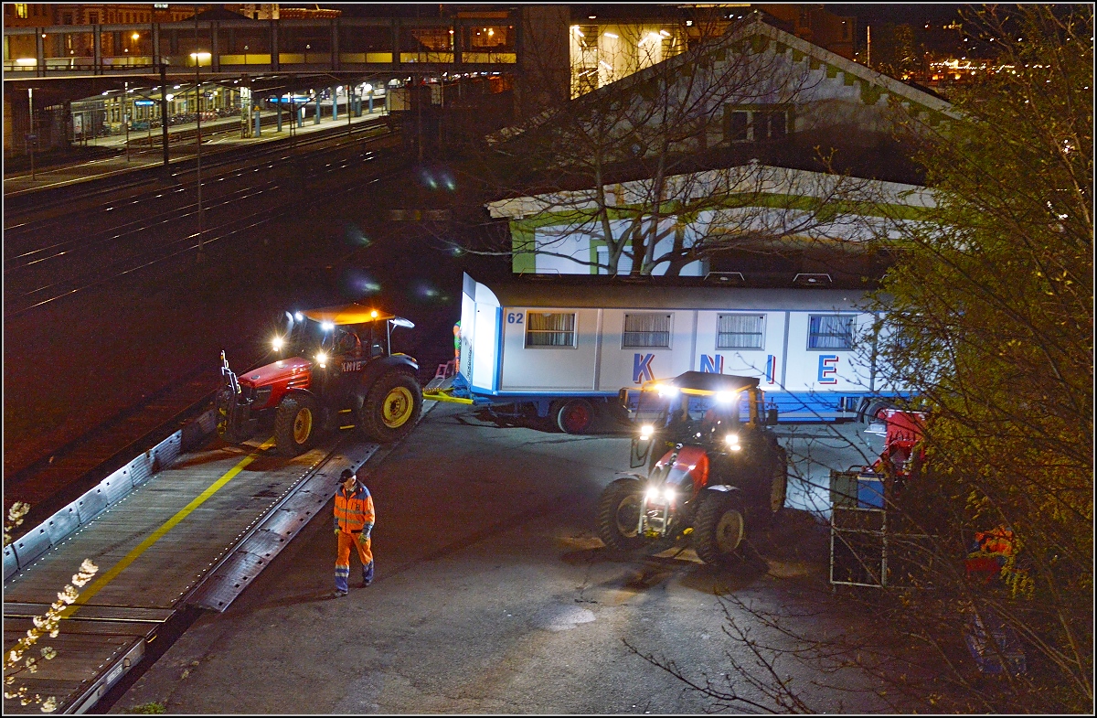 Aufladen des Zirkus Knie in Konstanz. Während ein Traktor den Wagen auf den Zug zieht, macht sich der zweite Traktor parat, um den Wagen zu schieben. April 2016.