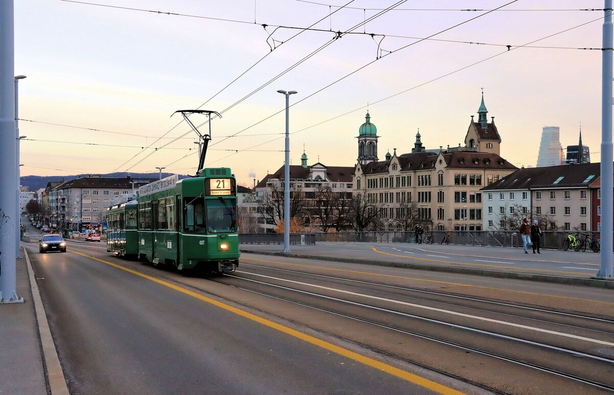 Bald endet der Einsatz von Vierachsern in Basel: Mit der Silhouette von Kleinbasel und einem Turm des Chemiekonzerns Roche im Hintergrund kommt Be 4/4 487 mit Anhänger 1463 auf die Dreirosenbrücke herauf. 7.Dezember 2021 