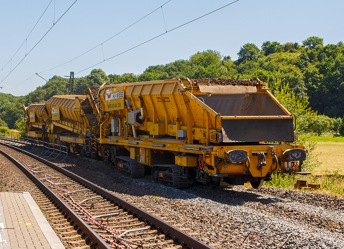 Baustelle im Bahnhof Katzenfurt (Lahn-Dill-Kreis) am 20.07.2013: Der MFS 40/4-A-ZW der H. F. Wiebe, Schweres Nebenfahrzeug 99 80 9052 002-9 D-GBM (ex 97 19 13 502 57-3) übergibt den Aushub an eine, auf dem noch vorhandenen Gleis stehenden, gleisgebundenen Materialförder- und Siloeinheit MFS 250 (H.F. Wiebe Bezeichnung Bunker-Schüttgut-Wagen BSW 11000).