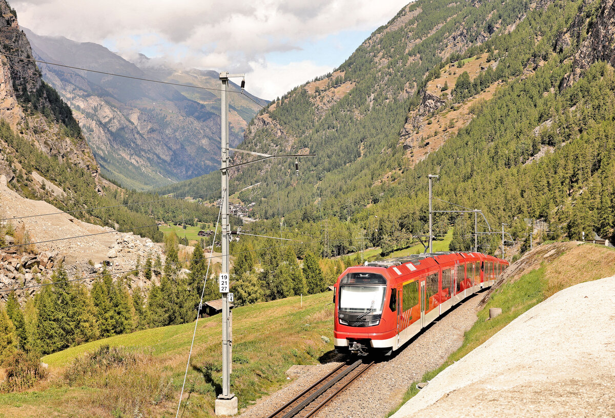 Der Bergsturz von Randa: Nachdem der talwärts fahrende Zug einigermassen flach den Scheitelpunkt der Umfahrungsstrecke passiert hat, geht es steil abwärts bis da, wo sich die einstige Strecke von Herbriggen her befand. Zu sehen sind die beiden  Orion - Triebwagen ABeh8/12 310 und 305. 30.August 2025 