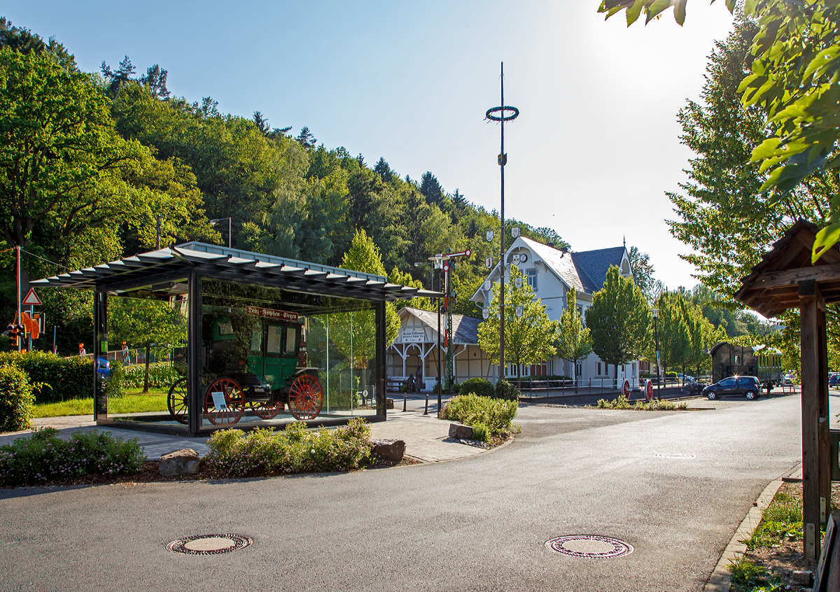 
Der ehemalige Bahnhof  Deuz (heute Netphen-Deuz) der Kleinbahn Weidenau–Deuz GmbH, am 19.06.2019. 
Die GmbH wurde am 4. Juni 1904 gegründet. Das Kapital brachten zu gleichen Teilen das Königreich Preußen, die Provinz Westfalen und der Kreis Siegen auf. Ziel war es, das Amt Netphen im oberen Siegtal mit einer Bahn (Johannlandbahn) zu erschließen.

Der Personen- und Güterverkehr auf dem 11,3 Kilometer langen Teilstück von Weidenau nach Deuz wurde am 1. Dezember 1906 aufgenommen. Die Fortsetzung bis Irmgarteichen-Werthenbach (4,8 km) folgte für Personenzüge am 1. Dezember 1916 und für Güterzüge am 21. Mai 1917.

Über mehrere Jahrzehnte entwickelten sich die Verkehrsleistungen positiv. Auch nach der Einstellung des Personenverkehrs am 25. Mai 1968 nahm der Güterverkehr noch zu.

Am 1. Januar 1970 wurde die Kleinbahngesellschaft Weidenau–Deuz GmbH aufgelöst und ihr Vermögen auf die Siegener Kreisbahn, jetzt: Kreisbahn Siegen-Wittgenstein übertragen, die mehr als 90 Prozent der Gesellschaftsanteile in Besitz hatte und schon seit dem 1. April 1955 Betriebsführerin war.

Erst in den Jahren ab 1990 begann der Rückgang, im Jahr 2004 führ der letzte Güterzug.

Der reguläre Betrieb der Strecke beschränkt sich heute auf den Bereich Weidenau Vorbahnhof bis Dreis-Tiefenbach, dort werden mehrere Industriebetriebe bedient. Mittlerweile endet das Gleis bei KM 2,9 im Werk Bombardier. Dieses stellt Drehgestelle für Eisenbahnen her, früher ganze Güterwaggons.

In Deuz wird noch seit 29. Mai 2004 im Walzenwerk Irle ein Inselbetrieb durchgeführt, dabei sind Werk 1 und 2 noch miteinander verbunden. Für den Werkverkehr ist die von OnRail aufgearbeitet und von der Fa. Irle gekaufte V 60 1175  (zuletzt DB 365 175-9) sowie acht Güterwagen vorhanden. In der Gießerei im Werk II (Gleislänge 320 Meter) werden die Walzenrohlinge abgeholt und zur Bearbeitung nach Werk I (Gleislänge 500 Meter) gebracht. Nach der Bearbeitung werden die Späne wieder zur Gießerei gefahren und die Fertigwaren kommen zum Versandgleis, ebenfalls in Werk II.

Links in dem Pavillon steht ein detailgetreuer Nachbau von erstem benzinbetriebene Omnibus der Welt der 1895 von der Firma Benz & Cie aus Mannheim gebaut und an die die „Netphener Omnibus-Gesellschaft mbH“ geliefert wurde.Technisch gesehen ist der erste Motoromnibus der Welt ein umgebautes Personenwagen-Modell mit einer so genannten Landauer-Karosserie – eine Aufbauart, die damals bei Kutschen weit verbreitet ist. Angetrieben wird er von einem liegenden Einzylinder-Motor im Heck, der 5 PS leistet. Der Antrieb erfolgt über Ketten an die Hinterräder. Der Bus bietet Platz für acht Personen inklusive Fahrer.

Die Idee ist so simpel wie genial: Weil sich seine Automobile zunächst nur schleppend verkaufen, sucht Carl Benz schon kurz nach der Erfindung des Automobils 1886 nach weiteren Einsatzmöglichkeiten für die neue Technik. Um den Kraftwagen größeren Kreisen zugänglich zu machen, erfindet Benz den Omnibus. Geliefert wird das weltweit erste Exemplar an die „Netphener Omnibus-Gesellschaft mbH“ im Siegerland, einer Region im heutigen Nordrhein-Westfalen. Am 18. März 1895 nimmt der erste Motor-Omnibus der Welt den Betrieb auf.

So kann das Netpherland für sich in Anspruch nehmen, die erste Omnibuslinie der Welt besessen zu haben. Der Omnibus war gleichzeitig auch das erste Nutzfahrzeug, das von der Fa. Benz hergestellt wurde.

Der Bus verkehrte zwischen 6.45 Uhr und 20.55 Uhr auf der Strecke Siegen-Netphen-Deuz. Betrieben wurde die Linie von einer Art Aktiengesellschaft. Der erste Bus verkehrte am 18.3.1895. Unlösbare technische Probleme und häufige Reparaturen zwangen die Gesellschaft, den Busverkehr bereits zum 20.12.1895 einzustellen.
