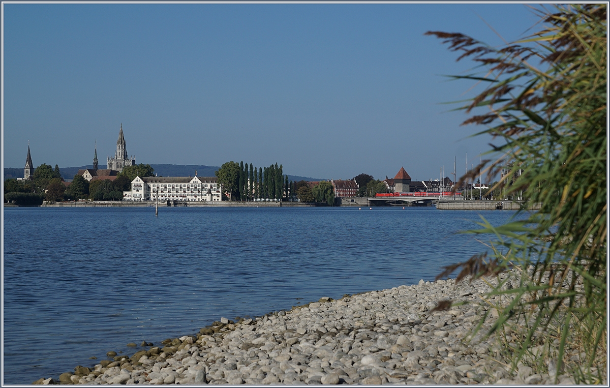 Der Rhein verbindet, der Rhein trennt; doch Brücken überwinden die Trennung. Nachdem der Alpenrhein bei Lustenau von der  neuen Eisenbahnbrücke über den Rhein ein letztes mal überbrückt wurde, fliesst er durch den Bodensee und wird just an jener Stelle, wo er wieder zum Rhein wird erneut überbrückt: Die  Alte Rheinbrücke  in Konstanz von 1860, die jedoch 1938 grundlegend umgebaut wurde. Bei einer Gesamtlänge von 127.8 Meter ist die Brücke mit 26.95 recht breit, wobei nach dem Verzicht auf den Ausbau auf Doppelspur der Bahnstrecke der dafür freigehalten Korridor 1957 genutzt werden konnte und somit heute neben fünf Fahrspuren für den Strassenverkehr der Bahn nur ein Gleis zur Verfügung steht, welches rege genutzt wird. Der Rhein, welcher hier den Bodensee verlässt und nun von Kilometer zu Kilometer gezählt wird, heisst hier Seerhein und somit wird die  alte Rheinbrücke  auch  Seerheinbrücke  genannt. Im Bild eine DB 146 mit einem  Schwarzwald  -RE.
19. Sept. 2018