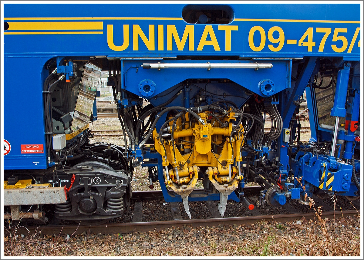 Detail, das Stopfagregat der Plasser und Theurer Universalstopfmaschine Unimat 09-475/4S  (Schweres Nebenfahrzeug Nr. 99 80 9424 001-2) der DGU - Deutsche Gleisbau Union (Koblenz), abgestellt am 15.03.2014 beim Bahnhof Siegen-Weidenau. Diese Aufnahme konnte ich vom Gehweg aus durch den Zaun machen.