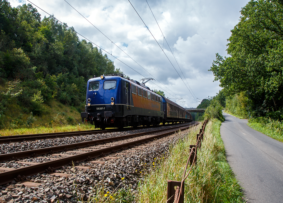 Die 139 287-7 (91 80 6139 287-7 D-BYB) der BayernBahn GmbH fährt am 26.08.2021 mit dem sogenannten  Henkelzug  (Langenfeld/Rhld. nach Gunzenhausen), bei Wissen (Sieg) über die Siegstrecke (KBS 460) in Richtung Siegen.

Die Lok wurde 1963 von Krauss-Maffei AG in München-Allach unter der Fabriknummer 18956 gebaut, er elektrische Teil ist von den Siemens-Schuckert-Werke (SSW) in Berlin. Als DB E10 287 wurde in Dienst gesetzt, mit der Einführung des EDV-Nummernsystems wurde sie zum 01.01.1968 zur DB 110 287–0. Die Lok ist mit Einholmstromabnehmern ausgerüstet, sie ist die letzte gebaute Kasten 110er. Zur 139er wurde sie erst 1994 nach einem Umbau, der Lokkasten wurde auf Drehgestelle der Baureihe 140 (E40) gesetzt und es folgte die Umzeichnung in DB 139 287-7. Zum Mai 2009 erfolgte die Z-Stellung bei der DB AG.

Zum 1.Oktober 2011 wurde die Lok durch die BayernBahn GmbH erworben und erhielt anschließend eine Untersuchung. Die Neulackierung in kobalt-blau/orange erhielt sie dann 2017. 