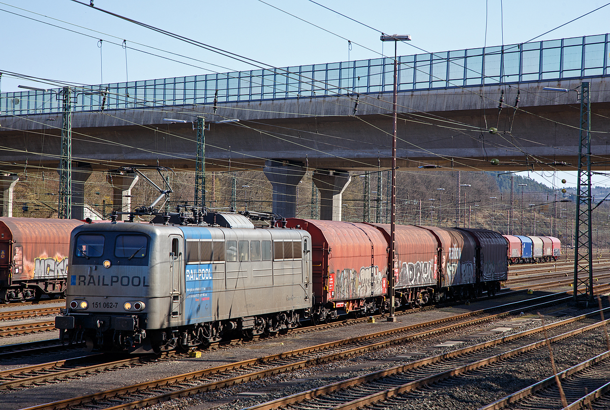 Die an die DB Cargo AG vermietete Railpool 151 062-7 (91 80 6151 062-7 D-Rpool) steht am 31.03.2021, mit einem kurzen Coilzug, im Rbf Kreuztal zur Abfahrt bereit.

Die Lok wurde 1974 von Henschel & Sohn in Kassel unter der Fabriknummer 31805 gebaut und an die Deutsche Bundesbahn geliefert. Bis 31.12.2016 gehrte sie zur DB Cargo AG. Zum 01.01.2017 wurden je 100 sechsachsige elektrische Altbau-Lokomotiven der Baureihen 151 und 155 an ein Konsortium aus dem Lokvermieter Railpool verkauft. Die DB Cargo mietet daraufhin 100 Loks von Railpool wieder an. Die anderen Maschinen werden dem freien Markt angeboten.

Wie auch die Werbung auf  ihr zeigt: Die Lok gibt es im Mastab 1:1 bei RAILPOOL und im Mastab 1:87 bei Roco und im Mastab 1:160 bei Fleischmann. Wobei mir persnlich gefllt sie in der Farbgebung nicht gerade. 
