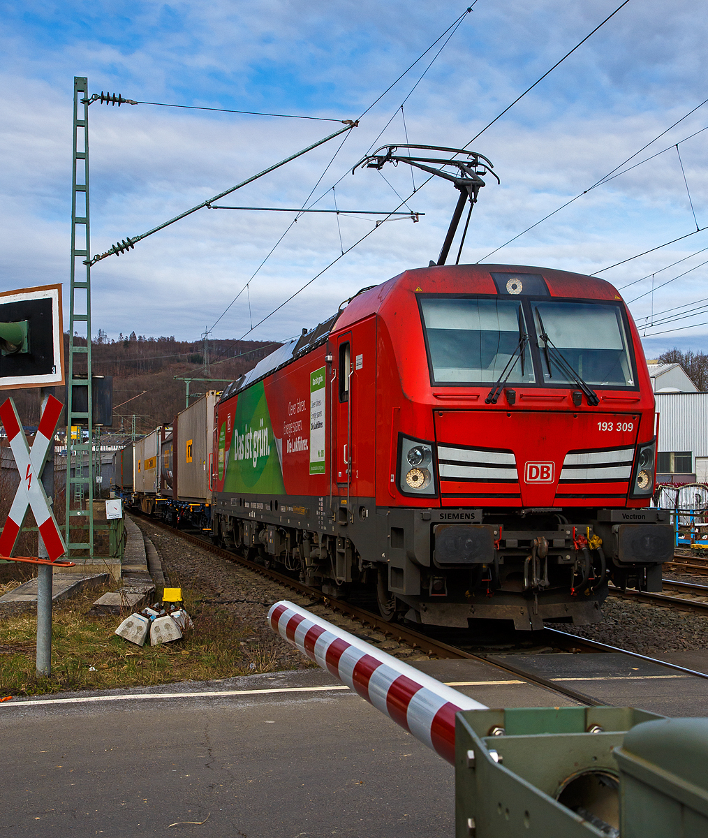 Die DB Cargo Vectron 193 309 (91 80 6193 309-2 D-DB) fährt am 20.03.2021 mit einem KLV-Zug über die Siegstrecke (KBS 460) durch Niederschelden bzw. Niederschelderhütte in Richtung Köln. Vor dem dem Bahnübergang befindet sich die Siegbrücke, die Sieg ist hier Bundes-Landesgrenze. So befinden sich hier im Bild die Lok in Rheinland-Pfalz, während die Wagen noch in Nordrhein-Westfalen sind. 

Die Vectron MS wurde 2018 von Siemens in München unter der Fabriknummer 22397 gebaut und an die DB Cargo geliefert.  Diese Vectron Lokomotive ist als MS – Lokomotive (Multisystem-Variante) mit 6.400 kW konzipiert und zugelassen für Deutschland, Österreich, Schweiz, Italien und Niederlande, sie hat eine Höchstgeschwindigkeit von 200 km/h. So ist es möglich ohne Lokwechsel vom Mittelmeer die Nordseehäfen Rotterdam oder Hamburg an zu fahren.