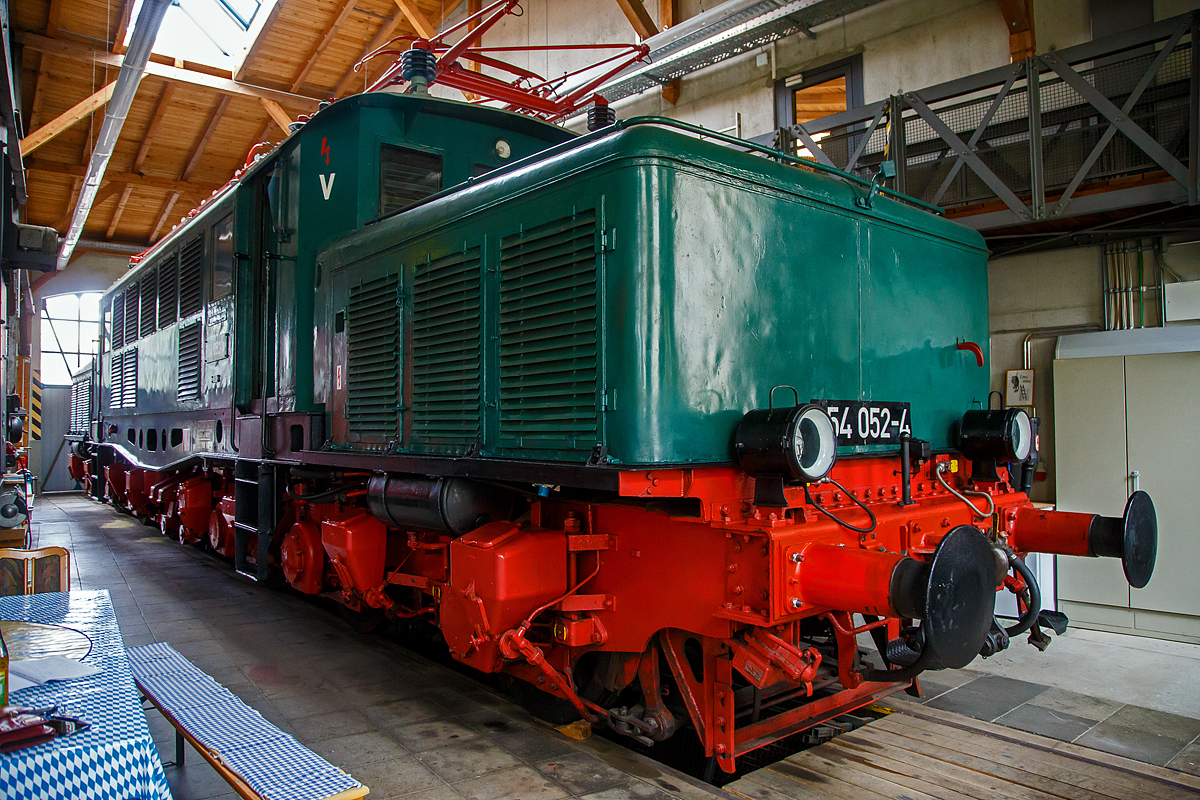 Die Güterzug-Elektrolokomotive 254 052-4 (97 80 9194 052-7 D -   ) des Vereins  Freunde des historischen Lokschuppens 1905 Freilassing e.V. , ex DR 254 052-4, ex DR E 94 052, ex SZD TEL 94-052, am 11.09.2022 in der Lokwelt Freilassing. 

Das Deutsche Krokodil wurde 1941 von der AEG (Allgemeine Elektrizitäts-Gesellschaft) in Hennigsdorf bei Berlin unter der Fabriknummer 5331 gebaut und im Januar 1943 an die Deutsche Reichsbahn geliefert.

Der Lebenslauf der Freilassinger Vereinslok 254 052-4:
• 11.12.1941  Endabnahme, Probefahrt von München Hbf zum Brenner und zurück.
• 12.12.1941  Auslieferung als DRB E 94 052 und bis April 1945 in Bayern
• April 1945 bis Mai 1946 beim Bw Probstzella in Thüringen
• Von Mai 1946 bis August 1952 als Reparationsleistung in die UdSSR (Sowjetunion) nach Workuta nördlich des Polarkreises als SZD TEL 94-052 (umgespurt auf Russische Breitspur)
• August 1952 bis Juli 1957 Wiederaufbau im  RAW Dessau, nach Rückgabe an die DR (DDR) in einem  grauenhaften Zustand, eingereiht als DR E 94 052. 
• Zum 01.07.1970 Umzeichnung in DR 254 052-4 
• Nach Führerhausbrand im August 1990, z-Stellung und zum 30.01.1992  Ausmusterung.
• Von 1994 - 1998  Standort Staßfurt (privat).
• Von 1998 - 2002 EFO Eisenbahnfreunde Oberberg, Standort EM Dieringhausen.
• Im Juni 2002 erfolgte die Betriebsfähige Aufarbeitung in Dessau, danach Vermietung an die PEG
• 2002 – 2006 als E 94.01der PEG - Prignitzer Eisenbahngesellschaft, Einsatz im Güterzugverkehr
• 2006  als 254 052-4Neulack im DR-Farbschema
• Fristablauf  zum 01.08.2010  
• 2010 – 2013 als E 94 052 bei LEG (Leipziger Eisenbahnverkehrsgesellschaft) und Leihgabe an das SEM (Sächsisches Eisenbahnmuseum) .
• Seit 2013 als Vereinslok 254 052-4 der Freunde des historischen Lokschuppens 1905 Freilassing e.V., Standort Lokwelt Freilassing, leider nur zu bestimmten zu besichtigen. 

Die Baureihe E 94 (ab 1968 DB-Baureihe 194, ab 1970 DR 254, ÖBB Reihe 1020) bezeichnet eine Baureihe sechsachsiger schwerenr Elektrolokomotiven der Deutschen Reichsbahn, die für den Güterzugdienst konzipiert waren und ab 1940 gebaut wurden. Außerdem sollten sie die Durchlassfähigkeit schwieriger Rampenstrecken, wie zum Beispiel der Geislinger Steige, der Frankenwaldbahn, der Arlbergbahn und der Tauernbahn erhöhen. Sie trugen den Spitznamen „Deutsches Krokodil“ manchmal auch „Eisenschwein“.

Die Co’Co’-Loks stellten eine direkte Weiterentwicklung der Baureihe E 93 dar, von der sich die E 94 äußerlich auf Anhieb durch die fischbauchförmigen und gelochten Langträger des Brückenrahmens sowie durch die andere Anordnung der seitlichen Fenster und Lüftungsgitter unterscheiden lässt. Die AEG lieferte bis zum Ende des Zweiten Weltkrieges 146 dieser auch KEL 2 (Kriegsellok) genannten Maschinen mit den Betriebsnummern E 94 001 bis 136, 145 und 151 bis 159. Beim Fahrzeugbau wurden zunehmend sogenannte Heimstoffe verwendet. Als Kriegslok hatte ihr Bau Priorität. Die Loks waren für 90 km/h Höchstgeschwindigkeit zugelassen.

Die Loks der Reihe E 94 waren in der Lage, Güterzüge mit 2.000 Tonnen in der Ebene mit 85 km/h, 1600 Tonnen über 10 Promille Steigung mit 40 km/h, 1000 Tonnen über 16 Promille mit 50 km/h und 600 Tonnen über 25 Promille mit 50 km/h zu ziehen.

Nach dem Zweiten Weltkrieg verblieben die meisten Loks bei der Deutschen Bundesbahn (DB). Aus vorhandenen Teilen wurden auch nach Kriegsende noch Lokomotiven fertiggestellt und bei der DB und den Österreichischen Bundesbahnen (ÖBB) in Betrieb genommen.

Die DB ließ zwischen 1954 und 1956 weitere Lokomotiven mit den Nummern E 94 178 bis 196 und E 94 262 bis 285 nachbauen und erwarb vier weitere von der Deutschen Reichsbahn, so dass sie insgesamt 124 Fahrzeuge im Bestand hatte. 1968 zeichnete die DB die E 94 gemäß ihrem Baureihenschema in die UIC-Baureihenbezeichnung 194 um.

Der Einsatz der Baureihe 194 bei der Bundesbahn beschränkte sich ausschließlich auf den süddeutschen Raum. Neben der Beförderung von Güterzügen waren sie als Schiebelokomotiven auf der Geislinger Steige und der Spessartrampe im Einsatz.

Die E 94 bei der DR nach 1945:
Im Bereich der Deutschen Reichsbahn waren 30 Lokomotiven verblieben, von denen aber zehn schadhaft abgestellt waren. Davon wurden nach dem Ende des elektrischen Betriebs (im März 1946) 25 Stück in die Sowjetunion als Reparationsgut verbracht, wie auch diese Lok hier. Dort wurden sie in der Mehrzahl für einen Versuchsbetrieb bei Perm auf 1.520 mm umgespurt und mit SA3-Mittelpufferkupplung ausgerüstet. Die nicht dafür ausgelegten Drehgestelle büßten dabei an Stabilität ein. Wegen des Platzmangels musste man auch die Radsterne abdrehen.

1952 und 1953 wurden von der UdSSR die 25 Lokomotiven wieder an die DR zurückgegeben. Wegen der geänderten Spurweite erfolgte das in der Regel in drei Teile zerlegt und auf Flach- bzw. Tiefladewagen verladen.

TECHNISCHE DATEN:
Spurweite: 1.435 mm (Normalspur)
Achsformel: Co’Co’
Länge über Puffer: 18.600 mm
Drehzapfenabstand: 10.000 mm
Achsabstand im Drehgestell: 4.600 mm
Treibraddurchmesser: 1.250 mm
Dienstgewicht: 118,7 t
Höchstgeschwindigkeit: 90 km/h
Stundenleistung: 3.300 kW
Dauerleistung: 3.000 kW
Anfahrzugkraft: 363 kN
Stromsystem: 15 kV 16⅔ Hz
Anzahl der Fahrmotoren: 6
Antrieb: Tatzlager
Bauart Fahrstufenschalter:  Handbetätigtes Nockenschaltwerk mit Zusatztrafo und Feinregler, eine halbe Umdrehung am Fahrstufenschalter bedeutete eine Fahrstufe
Bremse:  einlösige Druckluftbremse mit Zusatzbremse und elektrische Widerstandsbremse Kbr/K-GP m.Z. (Widerstandsbremse bei der DR ab 1981 ausgebaut)