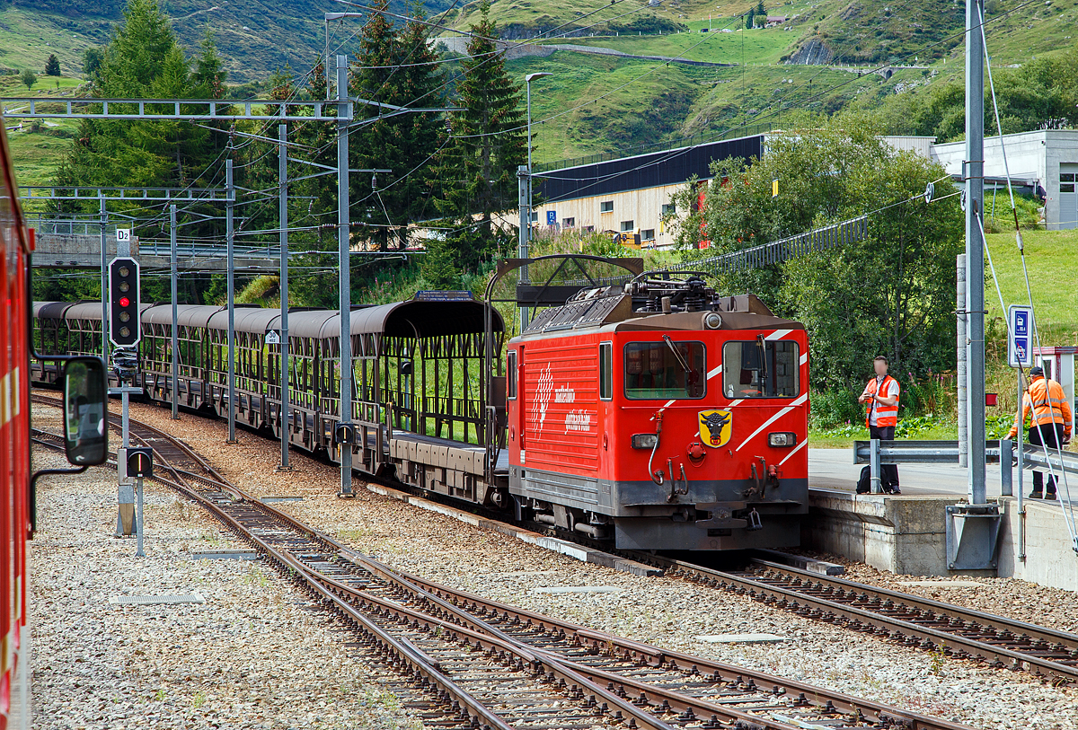 Die letzte, die Tunnellokomotive MGB Ge 4/4 III - 81 „Wallis“ der Matterhorn-Gotthard-Bahn ex FO MGB Ge 4/4 III - 81, steht am 07.09.2021mit einem Furka-Autoverladezug beim Bahnhof Realp (1.538 m ü. M.). 

Die Ge 4/4 III ist eine vierachsigen schmalspurige (1.000 mm) reine Adhäsions-Elektrolokomotive. Für die Beförderung der Autozüge durch den Furka-Basistunnel beschaffte die FO Furka-Oberalp-Bahn 1979 zwei vierachsige Schmalspurlokomotiven. Die Lokomotiven stellten eine Weiterentwicklung der RhB Ge 4/4 II der Rhätischen Bahn dar. Daher erhielten sie die Bezeichnung Ge 4/4 III, obwohl die FO keine weiteren Ge 4/4 besaß. Die Lokomotiven haben eine Leistung von 1.700 kW, eine Höchstgeschwindigkeit von 90 km/h und werden unter einer Fahrdrahtspannung von 11 kV, 16,7 Hz eingesetzt. Die Fahrzeuge sind die einzigen Streckenlokomotiven der MGB, die keinen Zahnradantrieb besitzen. Die MGB Ge 4/4 III - 81 „Wallis“ ist noch vorhanden, die Schwesterlok Ge 4/4 III - 82 „Uri“ wurde 2015 außer Betrieb gesetzt und als Ersatzteilspender für die 81 verwendet. Nachdem sie länger abgestellt war, erfolgte der Abbruch im November 2017. Einige Teile wurden für den Erhalt der Lok 81 eingelagert. Eines der beiden Urner Wappen von Lok 82 ist nun an einer Stirnseite der Schwesterlok 81 befestigt (wie hier im Bild zu sehen).

Die Lokomotive besitzt einen gesickten selbsttragenden Lokomotivkasten. Aus statischen Gründen musste die Einstiegstüre des Führerstandes nach hinten versetzt werden. Die Seitenwände haben keine Montageöffnung, sondern die ganze elektrische Innenausrüstung ist über die drei Dachluken eingebaut. Die Luftansaugöffnungen befinden sich auf dem Dach und sind für die Ausfilterung von Bremsstaub und feinem Flugschnee ausgelegt. Als Antrieb kam ein SLM-Schiebelagermotor zum Einsatz. Es handelt sich dabei um eine verbesserte Bauform eines Tatzlager-Antriebes, wobei sich der Motor eben auf kein festes, sondern ein seitenbewegliches Lager auf der Achse abstützt. Die beiden Schiebelager ermöglichen eine Axialverschiebung des Triebradsatzes. Somit wird der Radsatz in Querrichtung von der Masse des Motors entkoppelt. Die Schaltung des Hauptstromkreises entspricht weitgehend der RhB Ge 4/4 II, wobei im Traktionsstromrichter durch den technischen Fortschritt einige Vereinfachungen möglich waren. Auch in der Steuerung waren nur minimale Anpassungen erforderlich. Es ist deshalb auch möglich, mit der RhB Ge 4/4 II in Vielfachsteuerung zu verkehren
. 
Die Lokomotive besitzt für sich und die Autozug-Komposition eine Druckluftbremse. Diese ist mit einer Lufttrockungseinrichtung des Systems Lugart ausgerüstet, damit Bremsstörungen infolge der zum Teil doch harten Klimawechsel innerhalb und außerhalb des Tunnels vermieden werden können. Damit sie mit den übrigen Fahrzeugen verkehren kann, ist auch eine Vakuumbremse eingebaut. Als Handbremse bzw. Feststellbremse ist eine mit der Druckluft gekoppelte Federspeicherbremse eingebaut. 

TECHNISCHE DATEN:
Nummerierung: 	81, 82 
Spurweite: 1.000 mm (Meterspur)
Achsformel: Bo'Bo'
Hersteller: SLM Winterthur / 	BBC (technischer Teil)
Länge über Puffer: 12.900 mm
Höhe: 3.870 mm
Breite: 2.680 mm
Höchstgeschwindigkeit: 90 km/h
Dienstgewicht: 50 t
Stundenleistung: 1.700 kW
Treibraddurchmesser: 	1.070 mm (neu)
Anzahl der Motoren: 4
Steuerung:  Thyristor
Stromsystem: Einphasenwechselstrom 11.500 V / 16,7 Hz,

Geschichte:
Mit dem Bau des Furka-Basistunnels und dem Beschluss, ihn auch für den Autoverlad zu benutzen, war die Beschaffung der Autozugkompositionen zu evaluieren. Am Schluss blieb aus wirtschaftlichen Gründen eine konventionelle Lösung als Pendelzug mit einer Lok und Steuerwagen und dazwischen eingereihten Transportwagen. Als notwendige Transportkapazität wurden für Spitzenzeiten 100 Autos pro Stunde und Fahrrichtung angenommen, was zur Beschaffung zweier Kompositionen und damit dieser zwei Lokomotiven führte. 

Es wurden mehrere Varianten des Triebfahrzeugeinsatzes überprüft, darunter die Verwendung vorhandener Fahrzeuge mit und ohne Modernisierung. Dabei kam man zum Schluss, dass ein reines Adhäsionsfahrzeug der Bauart der RhB Ge 4/4 II die im Unterhalt kostengünstigste Lösung sei, wenn auch in der Anschaffung die teuerste Variante. 

Die FO ließ sich 1977 von der Industrie zwei Lokomotiven des Typs der RhB Ge 4/4 II offerieren, allerdings mit verstärkter elektrischer Bremse. Die Anbieter schlugen eine überarbeitete Lokomotive vor, die günstiger war, als die Ge 4/4 II vormals gekostet hatte. Die Änderungen gegenüber dem Referenzfahrzeug bezogen sich vor allem auf die Kastenbauform und den Antrieb. Die FO ging auf dieses Angebot ein. Zwischen der Ablieferung 1980 und der Inbetriebnahme des Furka-Basistunnels wurden die Lokomotiven an die RhB vermietet, die sie mit Schnellzügen auf der Albulalinie einsetzte. Seit 1982 werden sie ausschließlich für die Autozüge zwischen Oberwald VS und Realp UR verwendet. 

Eine Zugkomposition besteht aus:
An der Spitze des Zuges befindet sich immer auf der Seite Realp die Lokomotive. Es folgt ein Rampenwagen (Auffahrwagen) Sklv 4801 bis 4807, dann sechs Verladewagen (Sklv 4811 bis 4827), wieder ein Rampenwagen und als Abschluss ein Steuerwagen (BDt 4361bis 4363) auf der Seite Oberwald. Die Rampen- und Verladewagen sind mit Kuppelstangen fest zu einem Blockzug verbunden. Die Rampenwagen wiederum sind gegen die Lok und den Steuerwagen mit einer automatischen Kupplung +GF+, Typ Brünig, ausgerüstet.