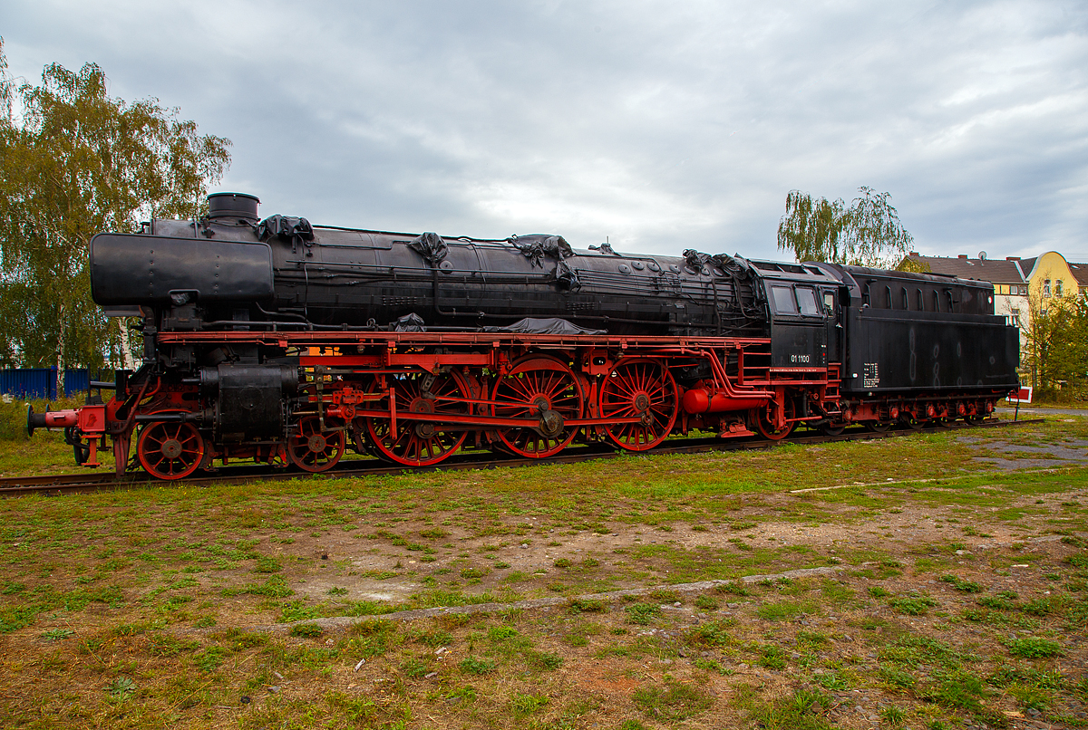 Die ölgefeuerte Dreizylinder-Schnellzug-Dampflokomotive 01 1100, ex DB 012 100-4, steht am 04.09.2020 im DB Museum Koblenz-Lützel. Die Lok wurde 1940 von der BMAG (Berliner Maschinenbau-Actien-Gesellschaft vormals L. Schwartzkopff), in Berlin unter der Fabriknummer 11356 gebaut und wurde an die Deutsche Reichsbahn geliefert. Am 31. Mai 1975 wurde die Lok bei der DB letztmalig planmäßig eingesetzt, zum 01.06.1975 erfolgte die z-Stellung und am 26.06.1975 die ausmusterung im Bw Rheine. 

Die Dampflokomotiven der Baureihe 01.10 waren von der Deutschen Reichsbahn im Rahmen des Einheitsdampflokomotiv-Programms beschaffte Schnellzuglokomotiven und eine Weiterentwicklung der Baureihe 01.

Die Deutsche Reichsbahn benötigte für ihr Netz schnellfahrender D- und FD-Züge leistungsstarke Dampflokomotiven mit einer Höchstgeschwindigkeit von 150 km/h. Es sollten Züge von 550 Tonnen in der Ebene mit 120 km/h sowie Züge von 425 Tonnen auf einer Steigung von 4 ‰ noch mit 100 km/h befördert werden.

Die bereits vorhandenen Lokomotiven der Baureihen 01 und 03 waren zwar nur für 120 bzw. 130 km/h zugelassen, konstruktiv jedoch bereits auf eine Höchstgeschwindigkeit von 140 km/h ausgelegt. Die starken Zuckbewegungen durch das Zweizylindertriebwerk dieser Baureihen ließen die höhere Geschwindigkeit jedoch nicht zu. Auch im Hinblick auf bessere Anfahreigenschaften entschied man sich zur Beschaffung von Maschinen mit laufruhigeren Dreizylindertriebwerken, dies ebenfalls wieder mit einfacher Dampfdehnung.

Zur Verringerung des Fahrwiderstandes wurden die Fahrzeuge mit einer bis 400 mm über Schienenoberkante heruntergezogenen Stromlinienverkleidung ausgerüstet. Durch diese konnte, wie Versuche mit der Baureihe 03 zeigten, die Zugleistung bei Geschwindigkeiten von 140 km/h um 48 ‰ gesteigert werden. Diese Mehrleistung bei höheren Geschwindigkeiten wurde bei der Baureihe 01.10 allerdings teilweise wieder durch die schlechtere Dampfversorgung des Dreizylindertriebwerkes im Vergleich zum Zweizylindertriebwerk aufgezehrt.

Bei einem berechneten Bedarf von 400 Lokomotiven wurden 1939 zunächst 204 Stück bei allen großen Lokomotivfabriken in Deutschland bestellt. Kriegsbedingt wurden jedoch nur 55 Lokomotiven ausgeliefert. Alle Maschinen stammten von Schwartzkopff (BMAG). 1944 wurden alle Lokomotiven wegen der Kriegsereignisse nach Westdeutschland verlegt. Nach dem Zweiten Weltkrieg befanden sich die Maschinen in einem desolaten Zustand. Vielfach fehlten Teile der Stromlinienverkleidung und die Kessel aus der als Kesselbaustoff nicht alterungsbeständigen Stahlsorte St 47 K zeigten erste Ermüdungserscheinungen. Am 20. Juni 1945 wurde die Ausmusterung über die gesamte Baureihe verfügt. Die Lokomotiven waren bis zu diesem Zeitpunkt jeweils weniger als 500.000 Kilometer gefahren. Aufgrund des herrschenden Lokomotivmangels nach dem Krieg griff man im Weiteren doch wieder auf die Baureihe zurück, einige Maschinen mit kleineren Schäden wurden vorläufig instandgesetzt.

Der Großteil der Lokomotiven blieb jedoch bis 1949 abgestellt. Im selben Jahr entschloss man sich, sämtliche Lokomotiven, bis auf eine (01 1067), die endgültig ausgemustert blieb, einer Aufarbeitung zu unterziehen. Im Rahmen dieser Aufarbeitung wurde die Stromlinienverkleidung von Lokomotive und Schlepptender vollständig entfernt und es wurden Windleitbleche der sogenannten Bauart Witte montiert. 

Ungelöst blieb das Problem der Kessel aus St 47 K, bei dem Schäden durch Ermüdungen und als Folge von Schweißungen auftraten. Da man im Betrieb auf die Maschinen nun nicht mehr verzichten konnte, entschloss man sich 1953, neue geschweißte Hochleistungskessel mit Verbrennungskammer in Auftrag zu geben. Diese wurden zwischen 1953 und 1956 bei Henschel in Kassel beschafft und im AW Braunschweig zusammen mit einer Mischvorwärmeranlage nach Bauart Heinl eingebaut. Die Verdampfungsleistung der über einen größeren Anteil an Strahlungsheizfläche verfügenden Neubaukessel war trotz geringerer Rost- und Gesamt-Verdampfungsheizfläche um rund 10 % höher als bei den Altbaukesseln. Bei den Maschinen mit Ölfeuerung waren Dampfverbräuche bis hinunter zu 5,8 kg/PSih möglich. 

1956 erhielt die 01 1100 zusammen mit dem neuen Kessel versuchsweise eine Ölhauptfeuerung. Mit dieser konnte die Leistung der Lok nennenswert erhöht werden, außerdem konnte die Ölfeuerung elastischer geregelt und damit den Betriebsverhältnissen besser angepasst werden. Die Maschinen waren daher wirtschaftlicher als kohlegefeuerte Dampfloks. Die Arbeit des Heizers wurde durch das Wegfallen des Kohleschaufelns erleichtert, da die Brennstoffzufuhr nun durch einen Schieber reguliert wurde. Der Heizer konnte überdies den Lokführer nun besser bei der Streckenbeobachtung unterstützen.

Verfeuert wurde das seinerzeit als Abfallprodukt vorhandene Schweröl (Bunker-C). Aufgrund der positiven Erfahrungen entschloss man sich 1957, weitere 33 Lokomotiven dieser Baureihe auf Ölfeuerung umzubauen. 1968 erhielten die kohlegefeuerten Lokomotiven bei der Umstellung auf das EDV-konforme Nummernsystem die Baureihenbezeichnung 011, die ölgefeuerten die 012.

Am 31. Mai 1975 wurden die letzten Maschinen der Baureihe, die teilweise Monatsleistungen von über 25.000 Kilometern und Gesamtkilometerleistungen von deutlich über 3,5 Millionen Kilometern erbracht haben, vom Bw Rheine letztmals planmäßig eingesetzt und anschließend unter Anteilnahme von Eisenbahnfreunden ausgemustert.

TECHNISCHE DATEN: 
Ausmusterung:  1975
Bauart:  2’C1’ h3
Gattung:  S 36.20 (Schweiz A 3/6)
Spurweite:  1.435 mm (Normalspur)
Länge über Puffer:  23.130 mm
Höhe:  4.550 mm
Leergewicht (ohne Tender):  101 t
Gewicht Lok und Tender: 177 t
Radsatzfahrmasse:  20 t
Höchstgeschwindigkeit:  vorwärts 150 km/h, rückwärts 50 km/h
Indizierte Leistung:  1.817 kW (ca. 2.470 PS)
Treibraddurchmesser:  2.000 mm
Laufraddurchmesser vorn: 1.000 mm 
Laufraddurchmesser hinten:  1.250 mm
Steuerungsart:  Heusingersteuerung mit Hängeeisen
Zylinderanzahl: 3
Zylinderdurchmesser:  500 mm 
Kolbenhub:  660 mm
Kesselüberdruck:  16 bar
Anzahl der Heizrohre:  119 
Anzahl der Rauchrohre: 44
Heizrohrlänge: 5.000 mm
Rostfläche:  3,96  m² 
Strahlungsheizfläche: 22 m²
Überhitzerfläche:  96,15 m² 
Verdampfungsheizfläche: 206,51 m² 
Tender:  2’3 T 38
Wasservorrat:  38,0 m³
Brennstoffvorrat:  13,5 t Schweröl
Zugheizung: Dampf
