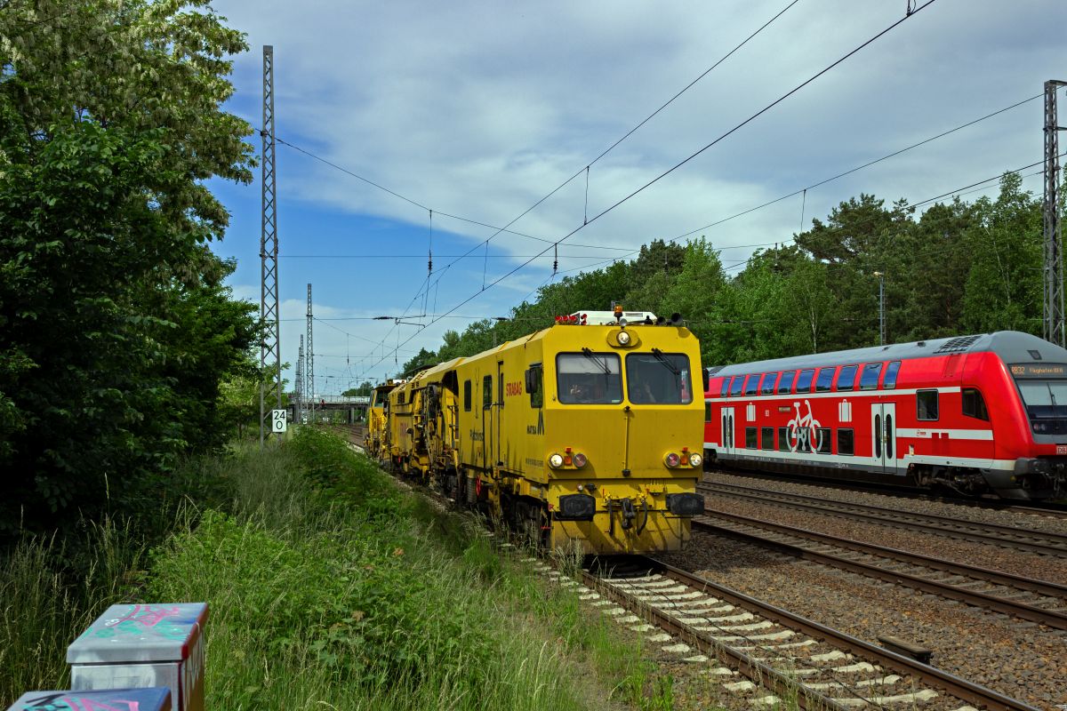 Eine Matisa-Stopfmaschine der Firma Strabag ist zur �berholung durch Fernverkehrsz�ge auf das Ausweichgleis im Bahnhof Ludwigsfelde geleitet worden und rollt nun auf das Ausfahrsignal zu. Die Besatzung freute sich offensichtlich �ber die Aufmerksamkeit des Fotografen und gr��te mit ausgiebiger Nutzung des Makrophons.