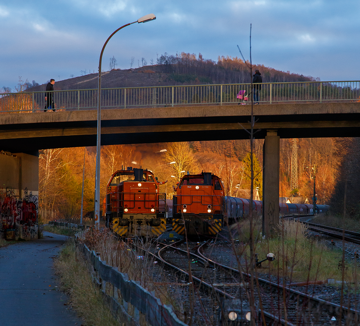 Freien Grunder Eisenbahn (KSW NE447 / DB-Nr. 9275) der Kreisbahn Siegen-Wittgenstein am spätem Nachmittag des 24.11.2021 in Herdorf:
Links fährt nun die die KSW 44 (92 80 1271 004-4 D-KSW) die MaK G 1000 BB durch den Rbf und weiter in Richtung Neunkirchen-Salchendorf. Rechts steht die KSW 42 (92 80 1277 902-3 D-KSW), eine Vossloh MaK G 1700 BB, mit einem Übergabe-Güterzug (von Herdorf zum Rbf Kreuztal) zur Abfahrt bereit.
