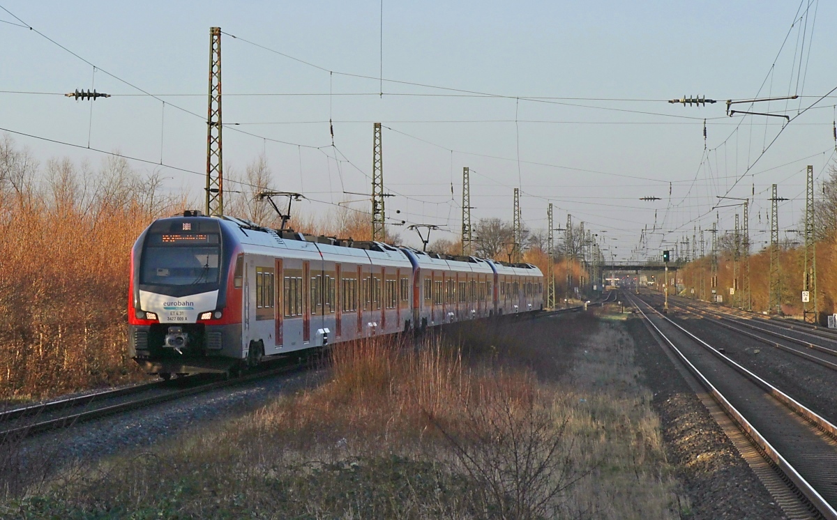 Für den elektrischen Betrieb auf der von der Regiobahn betriebenen S 28 von Kaarst nach Wuppertal hatte der Verkehrsverbund Rhein-Ruhr 10 Flirt 3 XL bestellt. Allerdings wird sich die Elektrifizierung der Abschnitte Kaarst - Neuss und von Düsseldorf-Gerresheim bis zur Einmündung in die Strecke Essen - Wuppertal-Vohwinkel noch um Jahre verzögern. Daher werden die Fahrzeuge momentan anderweitig im Verbund eingesetzt, u. a. auf dem von der Eurobahn betriebenen RE 3 Düsseldorf - Gelsenkirchen. Auf der Aufnahme ist eine Dreifachtraktion der Triebwagen mit dem ET 4.31/3427 009 zu sehen, die am frühen Abend des 23.02.2022 Düsseldorf-Angermund durchfährt.