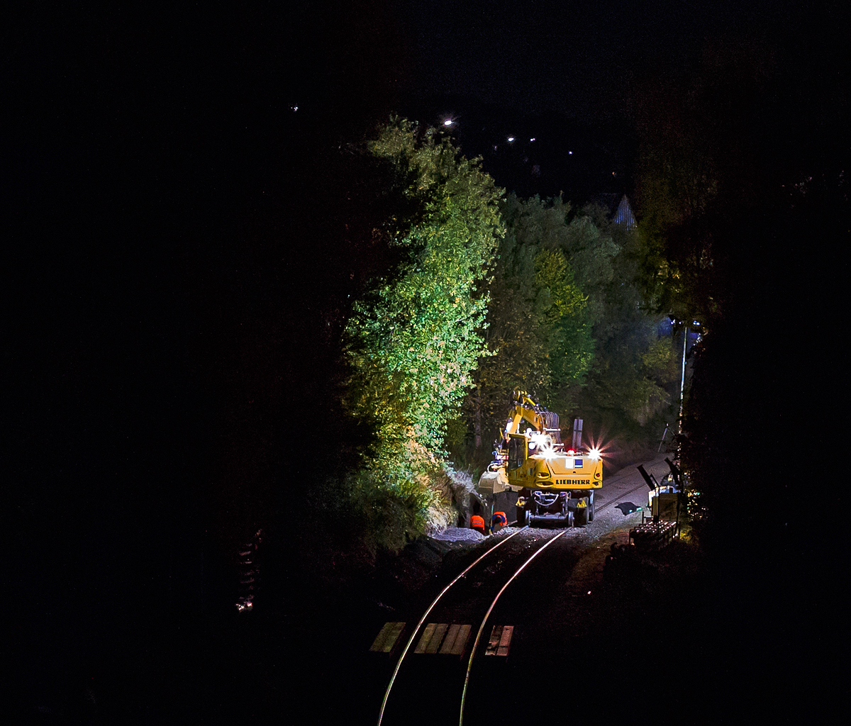 
Im Gleisbau wird Tag und Nacht gearbeitet, wie hier an der Hellertalbahn (KBS 462). Neben der Gleiserneuerung sind auch Nebenarbeiten erforderlich, so muss auch das Abwasser in die richtigen Bahnen geführt werden. Hier ist an Abend des 27.10.2020 ein Liebherr Zweiwegebagger A 900 C ZW Litronic der Hering Bau GmbH & Co. KG (57299 Burbach) in Neunkirchen-Altenseelbach im Einsatz.