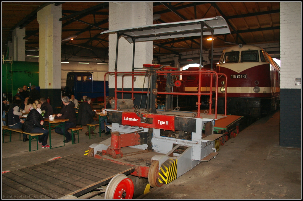 Im Lokschuppen stand dieser Breuer Lokomotor vom Typ III (TZp III). Bei dem Fahrzeug handelt es sich um ein leichtes Rangierfahrzeug mit Verbrennungsmotor, das 1913 von der Maschinen- und Armaturenfabrik vorm. H. Breuer & Co, Höchst am Main entwickelt wurde. Der Typ wurde in den Jahren 1924 bis 1929 gebaut und kam bei vielen privaten und Industriebahnen zum Einsatz. Die Funktionsweise ist dass das Fahrzeug mit einer Achse unter die Pufferbohle des zu rangierenden Fahrzeugs fährt und mittels einer Kupplungsklaue fixiert wird. Mit einer Handspindel wird die Klaue dann um 200 mm angehoben, was auch das Reibungsgewicht des Lokomotors erhöht hat. So konnten dann auch längere Wagen auf eine Drehscheibe gezogen werden ohne das es zu umständlichen Rangierfahrten wie mit einer Dampflok kam. Technische Daten TZp III: Länge 2870 mm, Breite 2900 mm, Höhe 2315 mm, Radstand 2570 mm, Dienstgewicht 3800 kg, Nennleistung 40 PS, max Zugkraft 350 t, Vmax 3 bis 15 km/h.