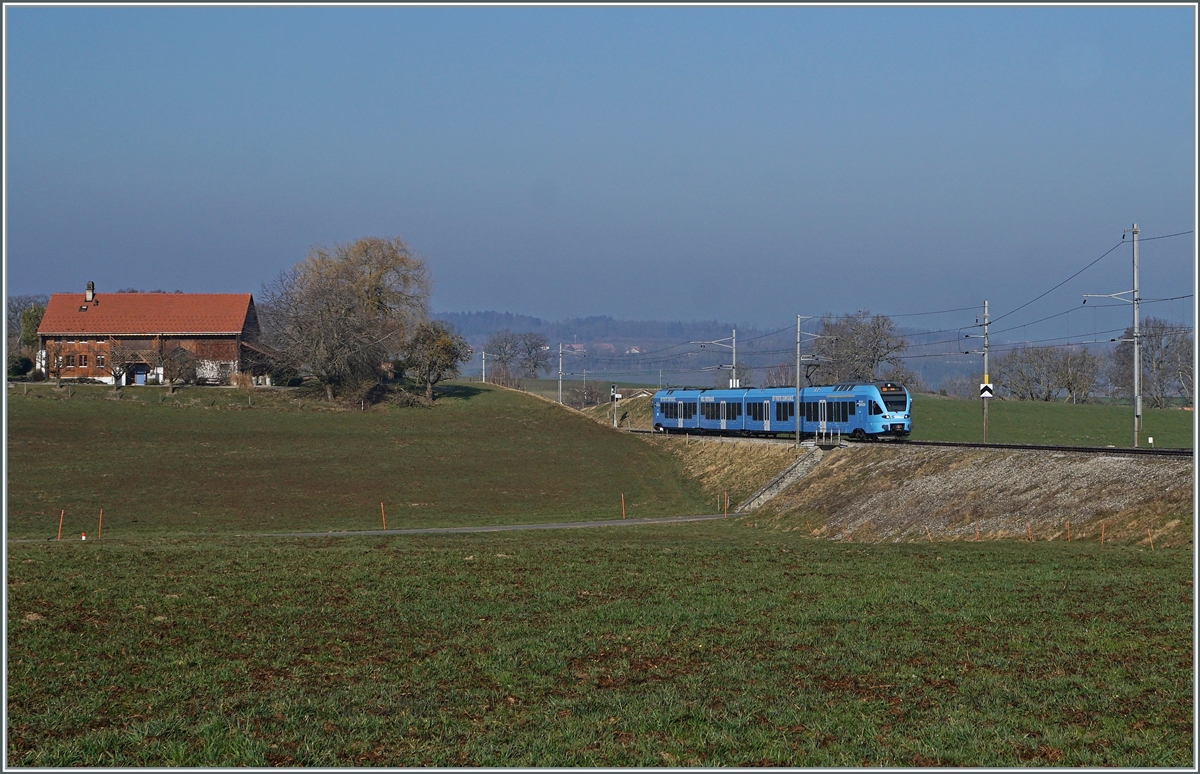 In weiten Kurven windet sich das Trasse der Strecken von Romont nach Vuisternens-devant- Romont, um die gut achzig Höhenmeter zu überwinden. Der im sehr gefälligen Werbeanstrich der  Groupe Grisoni  gehaltene TPF RABe 527 198 hat die Steigung fast geschafft und erreicht in Kürze den Bahnhof Vuisternas-devant-Romont, welcher jedoch wie alle Station zwischen Romont und Bulle nur noch dienstlichen Zwecken dienen.

1. März 2021 