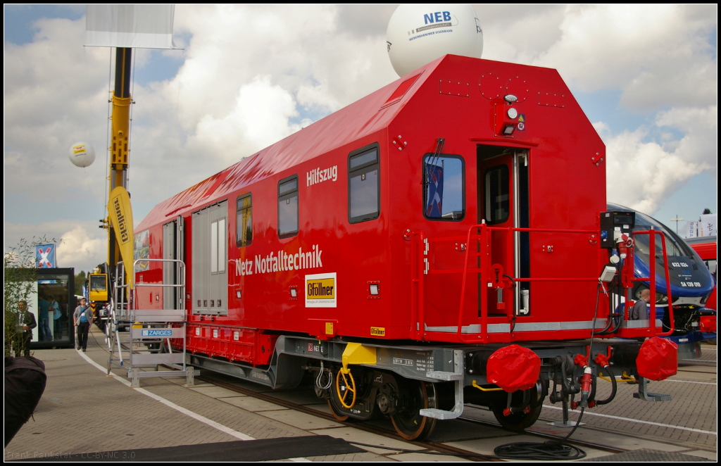 InnoTrans 2016 in Berlin: Bei dem Mannschaftswagen mit Werkstattabteil fr den Hilfszug der DB Netz Notfalltechnik handelt es sich eigentlich um einen Container, der von der Firma Gfllner Fahrzeugbau gebaut wird und mit einem Tragwagen geliefert wird. Der Container ist mit zwei Beobachtungsstnden ausgestattet, bietet Sitzgelegenheiten fr 6 Personen, Kleiderschrnke und eine kleine Kchenzeile. An beiden Seiten befinden sich Falttore mit ausschwenkbaren Hilfskrnen. Das Dieselaggregat ist in der Mitte des Containers untergebracht. Der Werkstattraum bietet Werkzeugschrnke, Werkbank, Lagerschrank fr Flssigkeiten, Acetylen und Sauerstoffflaschen (UIC-Nummer D-DB 99 80 9370 038-8 Hilfszugcontainer).