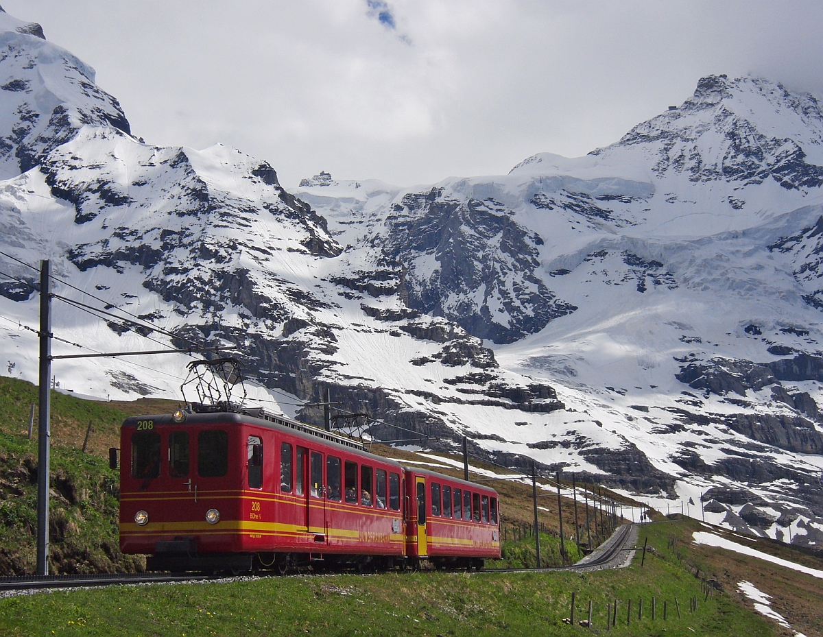 Mit Blick auf das 3454 m hohe Jungfraujoch in der Bildmitte fährt der 1964 in Betrieb genommene Triebwagen 208 der Jungfraubahn seinem Ziel und Fahrtende, der Kleinen Scheidegg entgegen. Von der 9 km langen Strecke vom Jungfraujoch zur Kleinen Scheidegg befindet sich der Triebwagen am 15.06.2013 auf dem insgesamt nur 2 km kurzen tunnellosen Abschnitt. Nach der Ankunft auf der 2061 m hoch liegenden Kleinen Scheidegg hat der Triebwagen in 50 Minuten Fahrzeit 1400 m Höhenunterschied hinter sich gebracht.