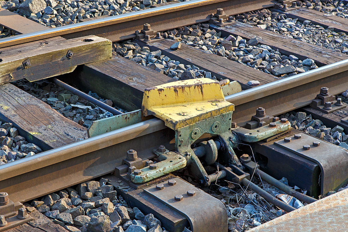 Nochmal Im Detail, die geschlossene Gleissperre hier an der Anschlustelle zum KSW-Gleis (Betriebssttte Freien Grunder Eisenbahn) in Herdorf am 20.03.2015. 

Das berfahren einer aufgelegten Gleissperre fhrt zum gewollten Entgleisen des Schienenfahrzeuges in die dem zu schtzenden Gleis entgegengesetzte Richtung. Der metallene Sperrklotz (Entgleisungsschuh) der Gleissperre kann nur durch Abheben eines Rades des Schienenfahrzeuges berrollt werden und das Fahrzeug in der „Auswurfrichtung” seitlich von der Schiene weg und so zum Entgleisen bringen.