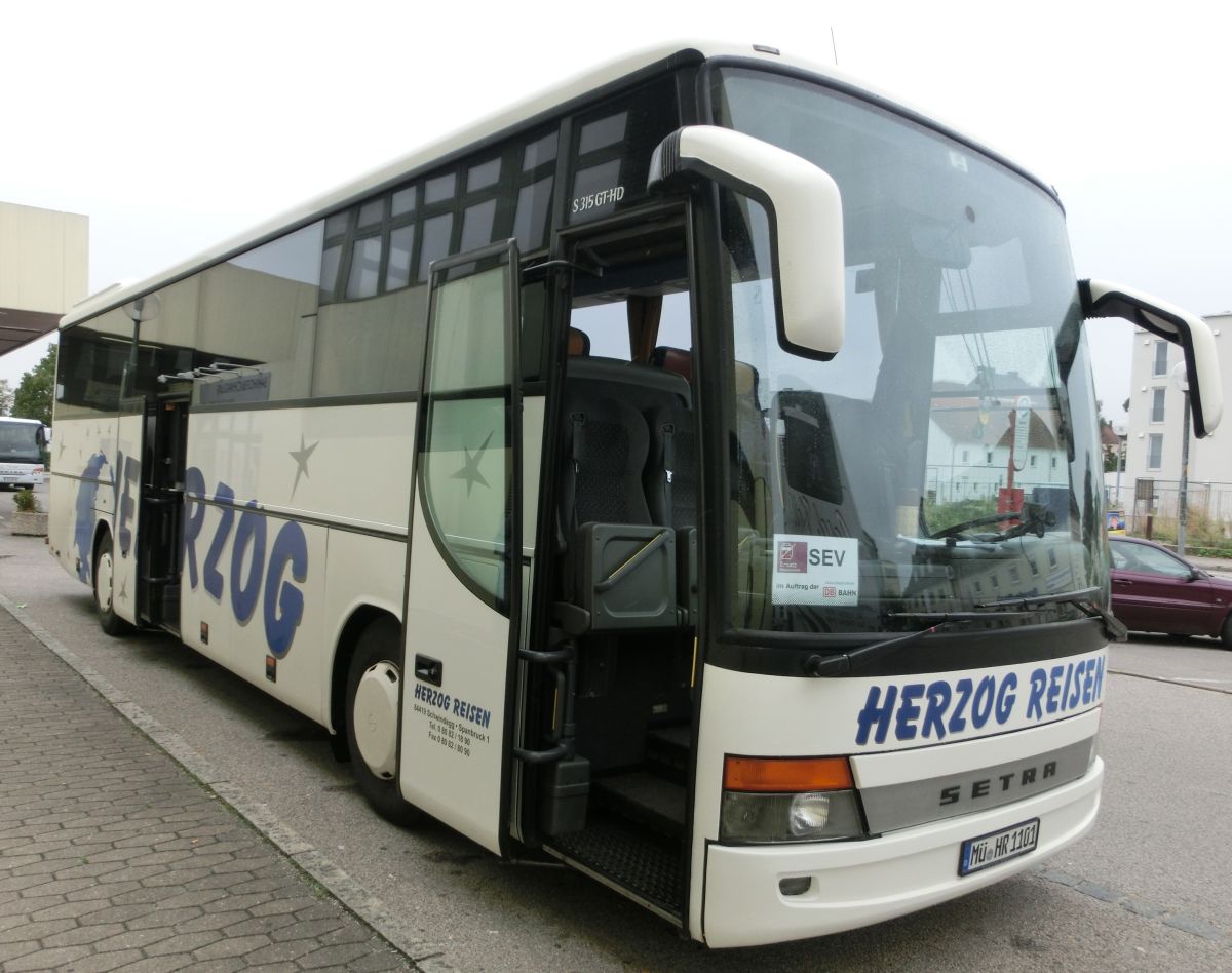 Setra S 315 GT-HD von Herzog Reisen aus Spanbruck bei Schwindegg. Da es sich um die Faceliftvariante handelt, ist er aus dem Bauzeitraum 2002-2004. Als Reisebus ist er selbstverständlich mit TV-Anlage, Bordküche und Toilette sowie mit 48+2 Setra-Schlafsesseln vom Modell 'Top' ausgestattet. Angetrieben wird er von dem stehend eingebauten Reihensechszylinder MB OM 457 LA und von dem MB-Sechsgang-Schaltgetriebe GO 190-6.
Ablichten konnte ich ihn am 28. 8. 2013 vor dem Mühldorfer Bahnhof, als er auf einem Schienenersatzverkehr zwischen Mühldorf und Dorfen (Bahnstrecke Mühldorf - München) eingesetzt wurde.
