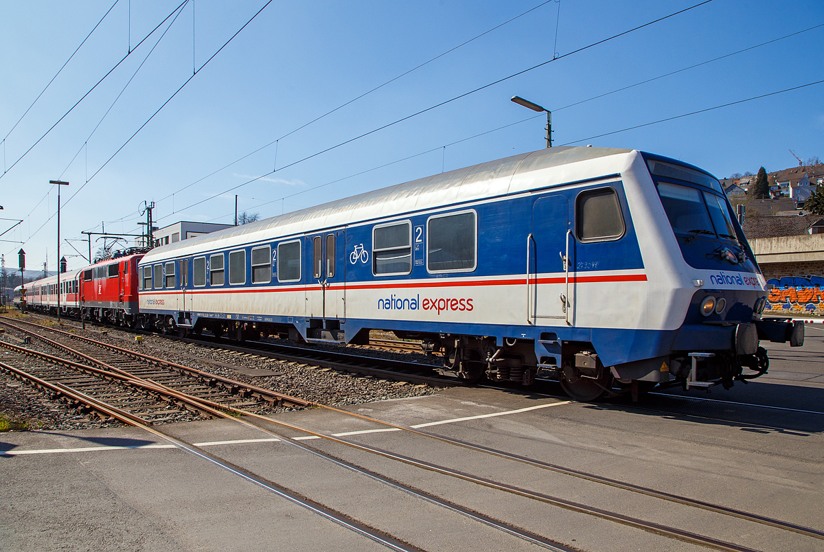 Steuerwagen voraus, Lok in den Zug eingereiht, fährt ein National Express Personenzug am 24.03.2021 durch Niederschelden, hier passiert er gerade den Bü 343 (Km 112,183 der Siegstrecke KBS 460).

Die Zugbildung war hier im Einzelnen: 
Der National Express 2.Klasse Nahverkehrs-Steuerwagen mit Wittenberger Kopf und Mehrzweckraum, D-TRAIN 50 80 80-35 128-3 der Gattung Bnrdzf 483.0 (ex BDnrzf 739.0. Der Wagen wurde 1995 vom AW Karlsruhe gebaut.
Die 111 200-2 (91 80 6111 200-2 D-GfF) der Gesellschaft für Fahrzeugtechnik mbH
Zwei National Express 2. Klasse Nahverkehrswagen (n-Wagen)
Am Zugschluss der National Express 2.Klasse Nahverkehrs-Steuerwagen mit Wittenberger Kopf und Mehrzweckraum, D-TRAIN 50 80 80-35 190-3 der Gattung Bnrdzf 483.1 (ex BDnrzf 740.2) der TRI Train Rental GmbH.  Der Wagen wurde 2003 vom AW Werk Delitzsch gebaut.

Die aus scheibengebremsten Steuerwagen der Bauart BDnrzf 739 und 740 umgebauten und mit einem Wittenberger Kopf ausgestatteten Wagen werden überwiegend als Bnrdzf 483 bezeichnet. 
Die bisher verwendeten Führerstände konnten nur entweder mit Diesel- oder Elektroloks eingesetzt werden. Um den Steuerwagen für die jeweils andere Traktionsart nutzbar zu machen, ist ein mehrstündiger Umbau des Führertisches erforderlich. Aus diesem Grund wurde Anfang der 1990er Jahre vom RAW Wittenberge der Prototyp eines neuen modularen Führerstandes entwickelt. Zum Einsatz kommt ein aus GFK vorgefertigtes Wagenkasten-Segment, in dem der mit der Baureihe 111 eingeführte DB-Einheitsführerstand installiert ist. Der Führerraum ist geräumig und übersichtlich gestaltet, zudem hat er seitliche Türen und eine verglaste Rückwand mit Dreh- oder Schiebetür, durch die der Blick vom Fahrgastraum nach vorne auf die Strecke möglich ist. Auf der technischen Seite wurde eine rechnergestützte Steuerung installiert, die den Betrieb sowohl mit der konventionellen Wendezugsteuerung als auch mit der neuen zeitmultiplexen Wendezugsteuerung, sowohl mit Diesel- als auch mit Elektrolokomotiven ermöglicht. Die Betriebsart wird lediglich umgeschaltet, es sind keine Umrüstungen mehr erforderlich. 

Die Wagen werden als „Wittenberger Kopf“ oder „Wittenberge-Steuerwagen“ bzw. „Wittenberger Steuerwagen“ bezeichnet.

TECHNISCHE DATEN des Bnrdzf 483.0 : 
Spurweite: 1.435 mm
Länge über Puffer:  26.400 mm
Wagenkastenlänge:  25.800 mm
Wagenkastenbreite:  2.825 mm
Höhe über Schienenoberkante: 4.050 mm
Drehzapfenabstand: 19.000 mm
Achsstand im Drehgestell:  2.500 mm
Drehgestell Bauart:  Minden-Deutz 432
Leergewicht:  32 t
Höchstgeschwindigkeit:  140 km/h
Bremsbauart: KE-GPR-A -mZ (D) [ep|NBÜ]
Sitzplätze:  76 in der 2. Klasse
Abteile: 2 Großräume 2. Klasse, 1 Mehrzweckraum 
Baujahre: 1995 bis 1995
Bemerkungen: uneingeschränkt dieselloktauglich
