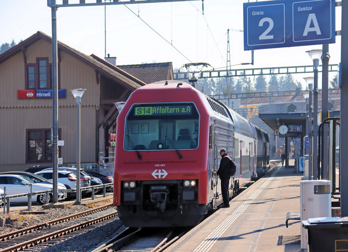 Zürcher S14, Wetzikon - Hinwil: Ein S-Bahnzug an der Endstation Hinwil. Von hier aus ginge es hinauf nach Bäretswil und Bauma, wo noch ein Museumsbahnbetrieb besteht (DVZO). Der Lokführer steigt ein in die Lok 450 064, die den bemerkenswerten Namen  City of Osaka  trägt. 5.März 2025 