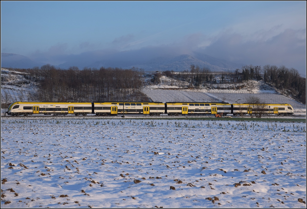 Zwischen Belchensystem und Blauendreieck. 

Ein Desiro HC von bwegt Richtung Basel bei Buggingen. Im Hintergrund befreit sich kurz vor Sonnenuntergang der Blauen aus seinen Nebeln. Februar 2021.