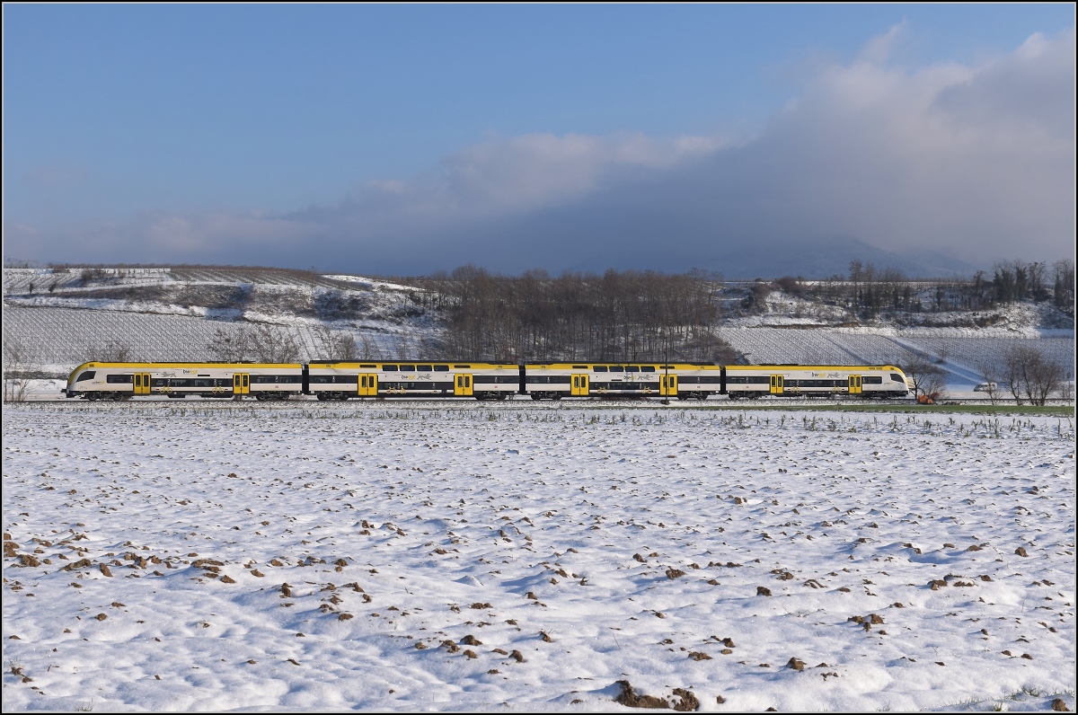 Zwischen Belchensystem und Blauendreieck. 

Ein neuer Desiro HC im bwegt-Design fährt südwärts, während sich einer der Protagonisten dieser Bilderserie langsam aus dem Nebel schält und dabei seinem Namen Blauen gerecht wird. Buggingen, Februar 2021.