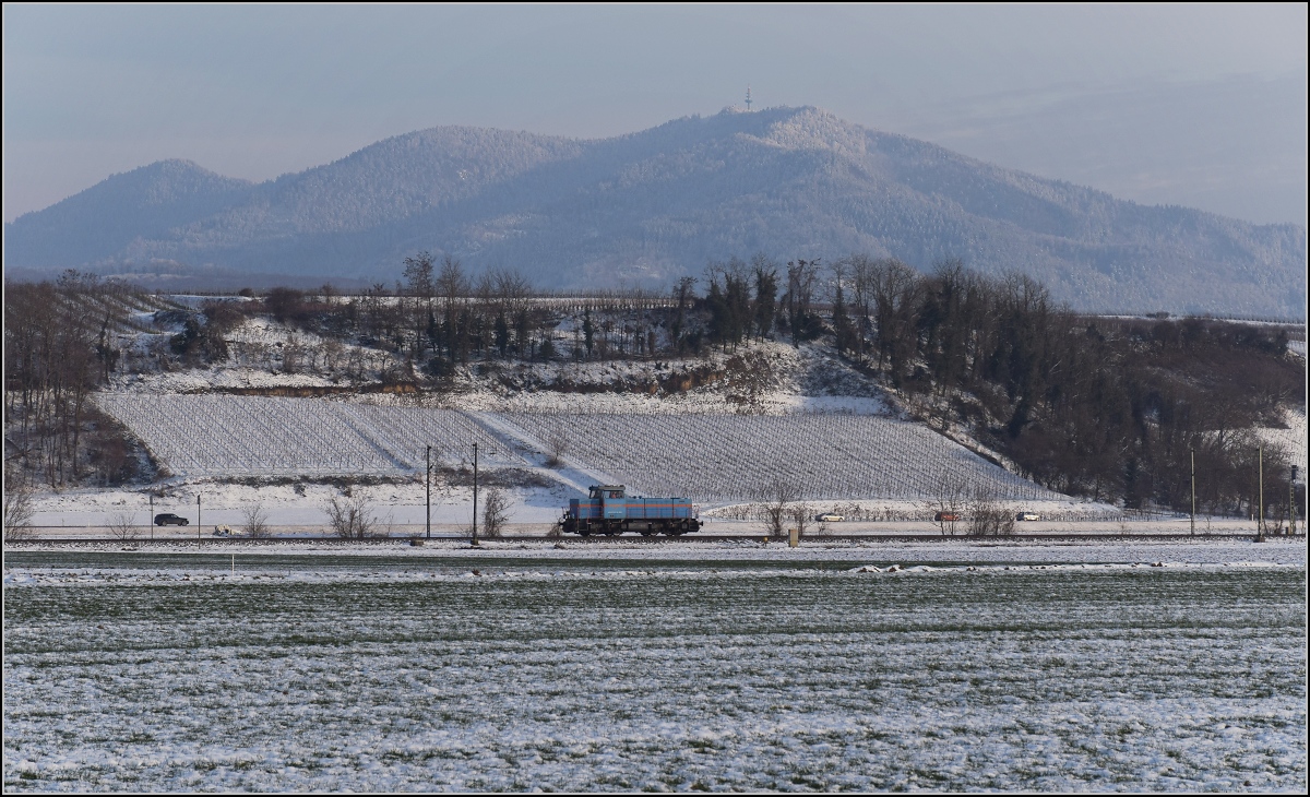Zwischen Belchensystem und Blauendreieck. 

Eine kleine Lok auf der Magistrale Richtung Basel wird kurz vorher Richtung Neuenburg abbiegen. 0 580 003 der SWEG lässt den Blick auf die Landschaft des Markgräfler Landes völlig frei. Im Hintergrund der prominente Blauen. Buggingen, Februar 2021.
