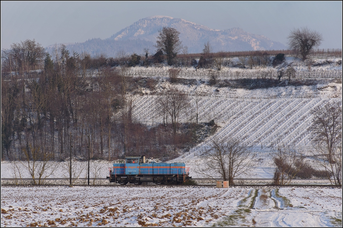 Zwischen Belchensystem und Blauendreieck. 

Eine kleine Lok auf der Magistrale Richtung Basel wird kurz vorher Richtung Neuenburg abbiegen. 0 580 003 der SWEG lässt den Blick auf die Landschaft des Markgräfler Landes völlig frei. Im Hintergrund das Belchen, Indikator für die Tag- und Nachtgleiche für die Kelten. Mit 1414 m die vierthöchste Erhebung im Schwarzwald, immerhin fast 1200 Meter über dem Standort des Fotografen. Buggingen, Februar 2021.