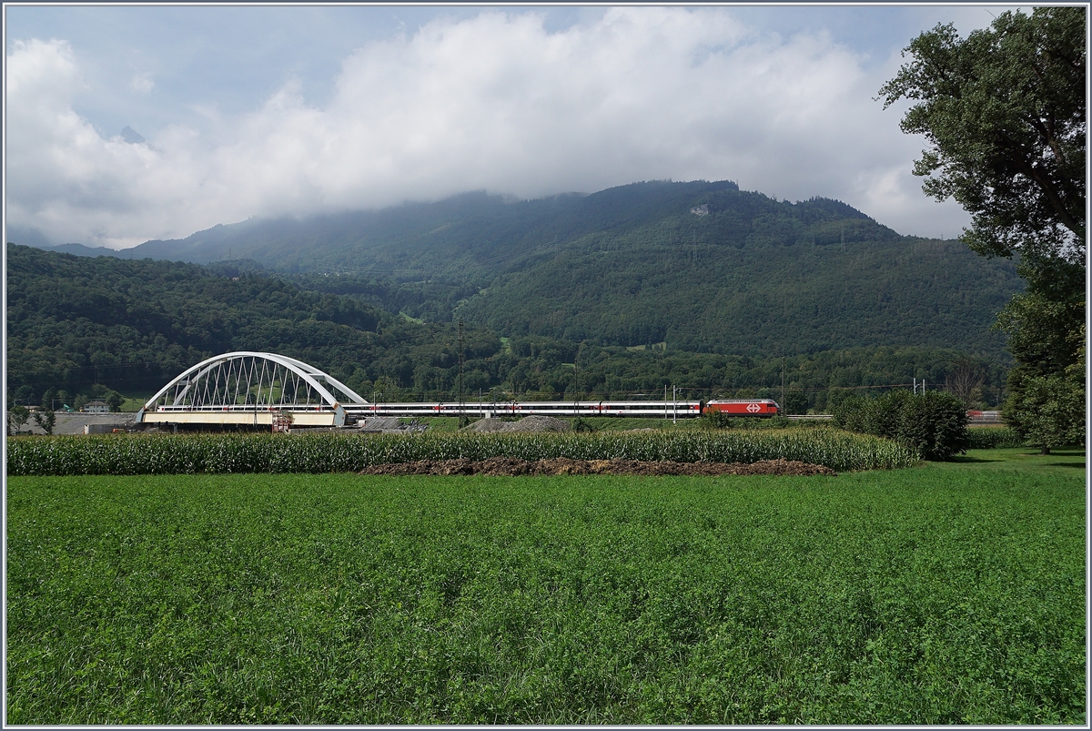 Zwischen Bex und St-Maurice überquert die Strecke Lausanne Birg die Rhone. Die alte Gittereisenbrücke wird nun durch eine sehr gefällige und unübersehbare Neukonstruktion ersetzt. Zu Zeit ist die alte Brücke schon nicht mir in Betrieb und der Verkehr verläuft einspurig über die neue Brücke, wobei vor und nach der Brücke das nördliche Gleis, dann auf der Brücke das Südliche Gleis benutzt wird, so dass die Brücke noch verschoben werden muss. Leider ist es nicht einfach, einen einigermasen guten Fotostandpunkt zu finden. Das Bild zeigt den von einer SBB Re 460 gezogenen IR 1716 von Brig nach Lausanne. 19. August 2016