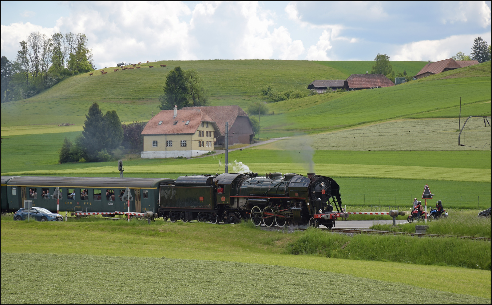 150 Jahre Emmentalbahn. 

141-R-1244 auf der RSHB-Strecke im Rahmen der grossen Emmentalrundfahrt zum Jubiläum. 

Nachdem der Scheitelpunkt der Strecke überschritten war, gab es wegen Bahnübergangsstörung in Weier einen Zwangsstopp. Ein Schrankenbaum wollte nicht schließen. Eine Demonstration, dass nicht nur im Nachbarland die Bahn an ihren Vorschriften erstickt. Man könnte meinen, mit einer roten Flagge sollte der Fall erledigt sein, die Autofahrer hatten ohnehin ganz brav alle angehalten. Nachdem sich im dritten Anlauf kein Erfolg eingestellt hatte, wurde der fehlbare Schrankenbaum von einem mittlerweile eingetroffenen grösserem Trupp Museumsbahner von Hand heruntergekurbelt. Es gibt offenbar viele Möglichkeiten, einen Bahnübergang zu bedienen. Die naheliegendste scheint aber nicht erlaubt, dem müssen sich auch die Museumsbahner beugen... Weier i.E., Mai 2025.