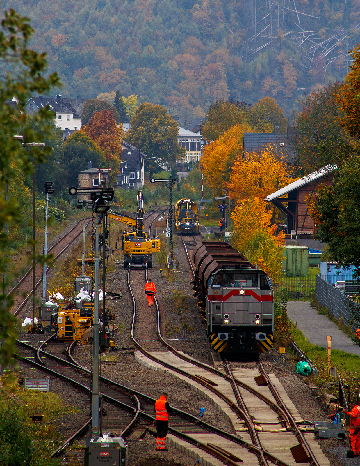 Blick auf den Bahnhof Herdorf und die Baustelle in Blickrichtung Betzdorf am 12 Oktober 2025. Die Weichen 25 und 26 sind beide eingebaut, müssen noch eingeschottert werden.

So steht die 277 809-0  Elmi“ (92 80 1277 809-0 D-KAF), eine Vossloh MaK G 1700 BB der KAF - Falkenhahn Bau AG (Kreuztal), steht mit einem Schotterzug bereit. Hinten beim Bahnhof haben die Schnellschotterplaniermaschine SSP 110 SW, Schweres Nebenfahrzeug Nr. 99 80 9425 068-0 D-DGU und die Universalstopfmaschine UNIMAT 09-475/4S, Schweres Nebenfahrzeug Nr. D-DGU 99 80 9424 001-2, den Bahnhof erreicht müssen aber nach das Einschottern abwarten. Beide Plasser & Theurer Maschinen gehören der Deutsche Gleisbau Union GmbH & Co. KG (DGU), Koblenz