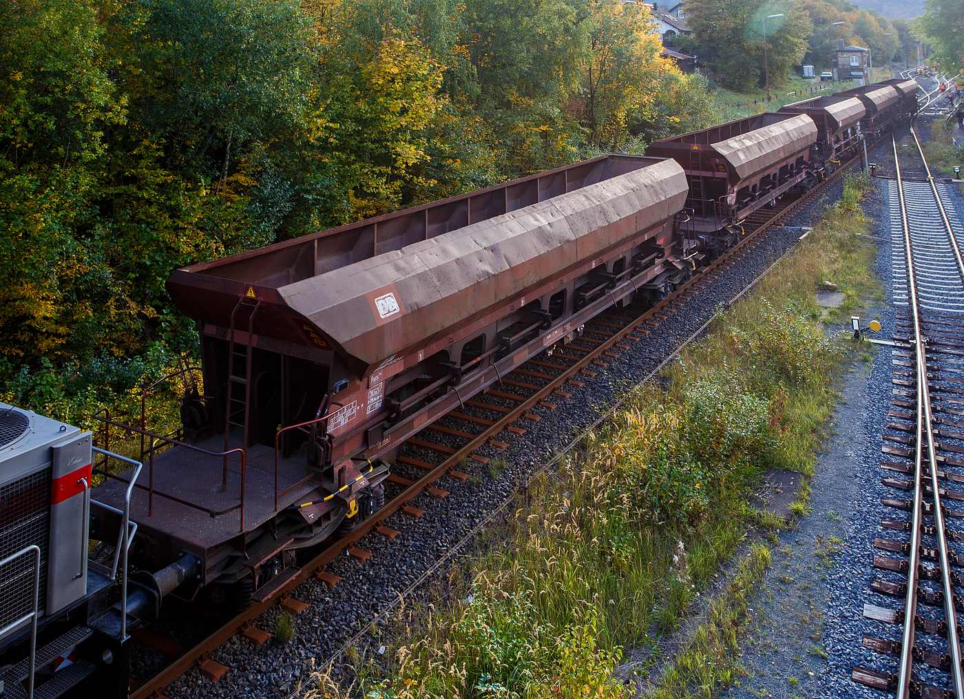 Blick seitlich von oben auf den vierachsigen offenen Drehgestell-Schüttgutwagen mit dosierbarer Schwerkraftentladung, 31 80 6940 387 D-DB, Gattung Facs 124 (ex DR Gattung Eads-y), der DB Cargo AG, steht 12 Oktober 2025, eingereiht in einen Schotterzug hier direkt hinter der Lok, im Bahnhof Herdorf.