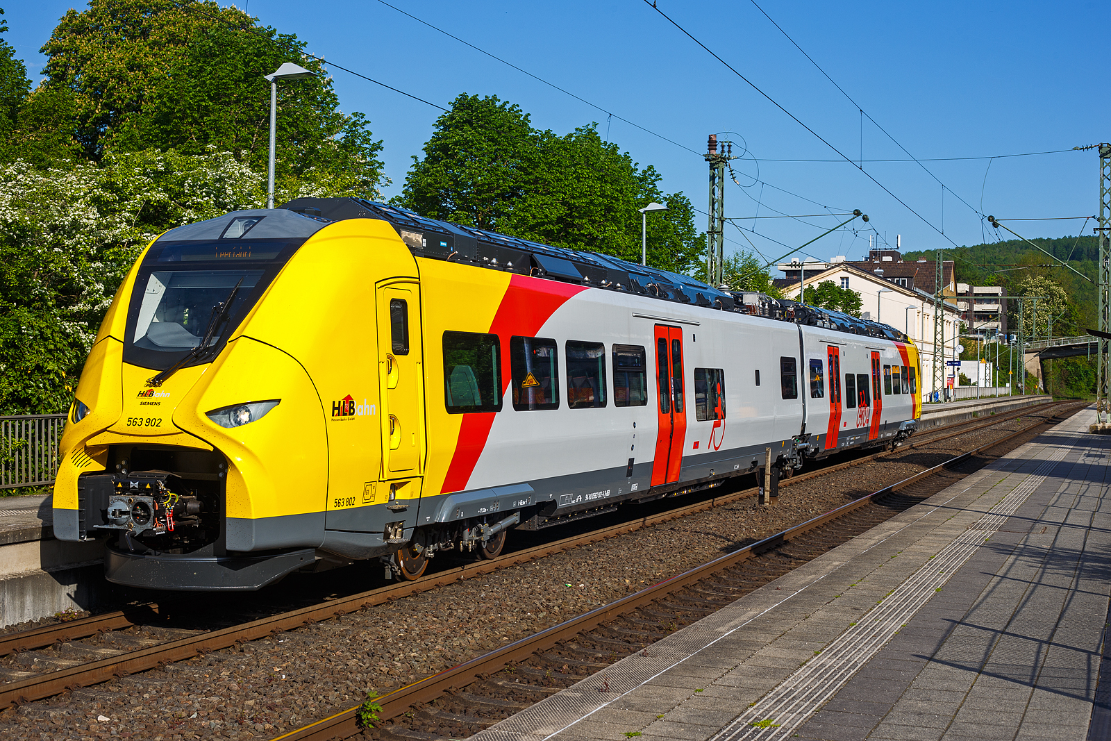 Das ist der neue Klimaschutz am Westerwald....
Einer der drei neuen zweiteiligen Hybridtriebzge (E/Akku) der BR 563 vom Typ SIEMENS Mireo Plus B der HLB (Hessische Landesbahn GmbH). Der HLB 563 802 / 563 902 (94 80 0563 802-8 D-HEB / 94 80 0563 902-6 D-HEB) fhrt am 02 Mai 2025 auf Leerfahrt durch den Bahnhof Kirchen/Sieg in Richtung Betzdorf, hier hat er kurz Hp 0. Der Triebzug fhrt hier sogar im Batteriemodus, denn es kein Stromabnehmer angehoben.  

Der zweiteilige SIEMENS Mireo Plus B wurden 2024/25 von SIEMENS in Krefeld gebaut und im April 2025 an die HLB ausgeliefert.

Auszug aus der Pressemitteilung der HLB:
Alternative Antriebe im Norden von Rheinland-Pfalz: Durchbruch beim Pilotprojekt mit Batteriezgen im Westerwald / Zuschlag an Siemens Mobility fr Mireo Plus B Fahrzeuge

Als Aufgabentrger fr den Nahverkehr auf der Schiene im Norden von Rheinland-Pfalz setzt sich der SPNV-Nord gemeinsam mit seinen Projektpartnern von Bund, Land und Eisenbahnverkehrsunternehmen (EVU) fr den Einsatz von alternativen Antrieben als Abkehr vom Dieselbetrieb ein.

Dabei konnte bereits im letzten Jahr fr die Beschaffung der Fahrzeuge eine Untersttzung aus dem Frderprogramm des Bundesministeriums fr Digitales und Verkehr (BMDV) fr alternative Antriebe gewonnen werden.

Als Besonderheit sollen im SPNV-Nord erstmalig die beiden Antriebstechnologien fr die Dekarbonisierung des Schienenverkehrs, Wasserstoff und Batterieelektrik, nebeneinander im mehrjhrigen Fahrgastbetrieb zum Einsatz kommen mit einer vollstndigen Rckfallebene mit Dieselfahrzeugen.

Das betrifft auch den Pilotbetrieb mit drei batterie-elektrischen Fahrzeugen im Westerwald, der zum Fahrplanwechsel im Dezember 2025 geplant ist. Dieser sieht einen Fahrzeugeinsatz auf der RB 90 Limburg – Au – Siegen (Oberwesterwaldbahn und Siegstrecke) und auf der RB 29 Limburg – Siershahn (Unterwesterwaldbahn) durch die Hessische Landesbahn (HLB) vor. Bei diesem Pilotprojekt wurde jngst ein wichtiger Durchbruch erzielt:

Als Ergebnis der von der HLB dafr durchgefhrten Fahrzeugausschreibung hat Siemens Mobility jetzt den Zuschlag fr drei zweiteilige Mireo Plus B Batteriezge erhalten. Das Fahrzeug mit seiner hohen Antriebsleistung ist fr den anspruchsvollen Einsatz im Westerwald bestens geeignet. Der geplante Einsatz der drei Batteriezge auf den Linien RB 90 und RB 29 umfasst eine Jahresfahrleistung von fast 400.000 Zug-km und ersetzt drei Dieselfahrzeuge. Da die HLB emissionsfreien Bahnstrom bezieht, werden jhrlich fast 1.150 Tonnen CO2 eingespart. Der Betrieb der Batteriefahrzeuge erfordert keine neue Infrastruktur, denn die Wendezeiten in Limburg von ber 20 Minuten auf der RB 29 werden fr die Aufladung der Fahrzeuge ausreichend sein. Bei den auf der RB 90 verkehrenden Batteriefahrzeugen erfolgt dies im elektrifizierten Abschnitt zwischen Au und Siegen. Die Oberwesterwaldbahn (Limburg – Au) ist mit der Lnge von rund 75 km und der zu berwindende Hhe von ca. 350 m derzeit in Deutschland die anspruchsvollste Strecke fr den vorgesehenen Einsatz von Batteriezgen.

Die Ausschreibung der Batteriefahrzeuge war so ausgestaltet, dass die Hersteller die Mglichkeit hatten, die Fahrzeuge in laufende Bestellungen zu integrieren, so dass eine schnelle Lieferzeit in Aussicht gestellt wurde.

Siemens Mobility baut fr den Einsatz im Westerwald drei zweiteilige Mireo Plus B Batteriezge, die durch jeweils drei Tren pro Seite einen schnellen Ein- und Ausstieg ermglichen. Die Zge verfgen fr den Betrieb unter Oberleitung und zum Aufladen der Batterien ber einen Stromabnehmer und verkehren auf den nicht-elektrifizierten Strecken im Batteriebetrieb. Die gerumigen Fahrzeuge bieten den Fahrgsten 126 Sitzpltze und 156 Stehpltze und sind mit einer speziellen Einstiegshilfe ausgestattet, die mobilittseingeschrnkten Menschen das Bahnfahren erleichtert.

Die neuen Batteriezge werden auf der Oberwesterwaldbahn Limburg – Altenkirchen - Au - Siegen, und auf der Unterwesterwaldbahn zwischen Limburg – Montabaur – Siershahn unterwegs sein. Die Strecke der OWB betrgt ca. 115 km, davon sind ca. 75 km ohne Fahrdraht. Es ist vorgesehen die Zge in Limburg und auf dem Teilabschnitt Au – Siegen nachzuladen. Auf der UWB betrgt die nicht elektrifizierte Strecke ca. 35 km. Damit ist ein Zugbetrieb hin und zurck ohne Nachladen mglich. Insgesamt werden die Zge ber 50 Bahnhfe anfahren.

Technik und Fahrzeugaufbau:
Die Triebzge werden nur mit elektrischem Antrieb angeboten. Die Fahrzeugplattform ist mit Jakobs-Drehgestellen und Einzeldrehgestellen, hnlich wie bei den ICE 4 mit innengelagerten Radstzen lieferbar. Die Wagenksten werden in Aluminium-Integralbauweise hergestellt. Bei diesem zweiteiligen Triebzug ruht je ein Wagenkasten auf einen Triebdrehgestell SF 7500 als Enddrehgestell, sowie auf der Hlfte des mittigen Jakobs-Laufdrehgestell SF 7500. 

Die Triebzge werden im Siemens-Werk Krefeld gefertigt. Im Mrz 2020 erhielt Siemens Mobility den ersten Auftrag fr eine zweiteilige Variante des Mireo Plus B die ihren Fahrstrom sowohl aus einer Batterie als auch aus der Fahrleitung erhlt. Die Batterie kann im Stand und whrend der Fahrt aus der Fahrleitung geladen werden. Die Reichweite eines Mireo Plus B im Batteriebetrieb wird mit 80 bis 120 Kilometern angegeben.

Zum Einsatz kommen Lithiumtitanat-Akkumulatoren (LTO) von Toshiba, die unter den Wagenbden verbaut sind. Diese haben eine hohe Zyklenfestigkeit auch bei hohen Ladestrmen, wie sie beim Bremsen und Anfahren auftreten – bei einer Laderate von 10C garantiert der Hersteller seit 2019 mindestens 15.000 Ladezyklen und seit 2022 mindestens 40.000 Ladezyklen.

Unterwesterwaldbahn/Oberwesterwaldbahn:
Am 7. Februar 2023 gab Siemens Mobility bekannt, dass die Hessische Landesbahn (HLB) fr den Einsatz auf den Regionalbahn Linien RB 29 (Limburg (Lahn)–Montabaur–Siershahn) und RB 90 (Limburg/Lahn–Au/Sieg– Siegen) auf der Unterwesterwaldbahn bzw. Oberwesterwaldbahn drei Mireo Plus B bestellt habe. Der Einsatz ist ab Sommer 2025 geplant und soll im Rahmen eines Pilotbetriebes die Eignung von Triebzgen mit alternativen Antrieben auf den topografisch anspruchsvollen Strecken demonstrieren. Der Betrieb soll nach Angaben der HLB jhrlich fast 1.150 Tonnen Kohlenstoffdioxid einsparen.

TECHNISCHE DATEN:
Spurweite: 1.435 mm (Normalspur)
Achsfolge: Bo’-2’-Bo’
Fahrzeuglnge ber Kupplung: 46.560 mm
Drehzapfenanstand: 2 x 17.930 mm
Achsabstand im Triebdrehgestell (Enddrehgestell): 2.300 mm
Achsabstand im Jakobs-Laufdrehgestell: 2.600 mm
Drehgestellplattform: SF 7500 mit innengelagerten Radstzen
Raddurchmesser: 880 mm (neu) / 810 mm (abgenutzt)
Anzahl der Tren je Seite: 3
Eigengewicht im betriebsbereiten Zustand: 92.891 kg
Installierte Leistung: 1.700 kW
Leistungsbertragung: elektrisch
Motoren: 2 Drehstrom-Asynchronmotoren
Hchstgeschwindigkeit: 140 km/h 
Kupplung: Mittelpufferkupplung Schaku Typ 10
Sitzpltze: 126
Bremse: FT C-el-pn-R-A-E-Mg (D)
kleinster befahrbarer Gleisbogen: R 150 m (Normal) / R 100 m (Werkstatt)
Zulassungen: Deutschland (D)

Ein kleiner Nachteil gegenber den LINT-Dieseltriebzgen ist mir aufgefallen, die Gesamt-Fensterflche ist geringer. Ich bin aber sehr gespannt auf den Betriebseinsatz und wie es luft.
