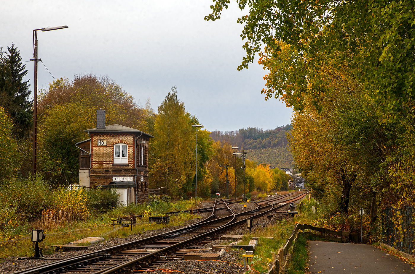 Das1901 gebaute mechanische Weichenwärter Stellwerk Herdorf Ost (Ho), an der Bahnstrecke Betzdorf - Haiger (KBS 462 „Hellertalbahn“), hier am 03.11.2022. 

Ja, in Herdorf gibt es immer noch den Luxus von zwei in Betrieb befindlichen Stellwerken, hier links das Weichenwärter Stellwerk Herdorf Ost (Ho) und weiter hinten das ca. 600 m entfernte Stellwerk Herdorf Fahrdienstleiter (Hf). Dazwischen der eigentliche Bereich vom Bahnhof Herdorf (Empfangsgebäude ist rechts von den Gleisen nicht im Bild). Neben meinem Standort, befindet sich die Weiche zur Anschlussstelle KSW (ex Freien Grunder Eisenbahn), so ist diese hier in meinem Rücken.

Da die Stellwerkstechnik in Herdorf noch rein mechanisch ist, werden beide noch benötigt, bzw. ein Umbau auf ein Stellwerk ist wohl zu aufwendig.