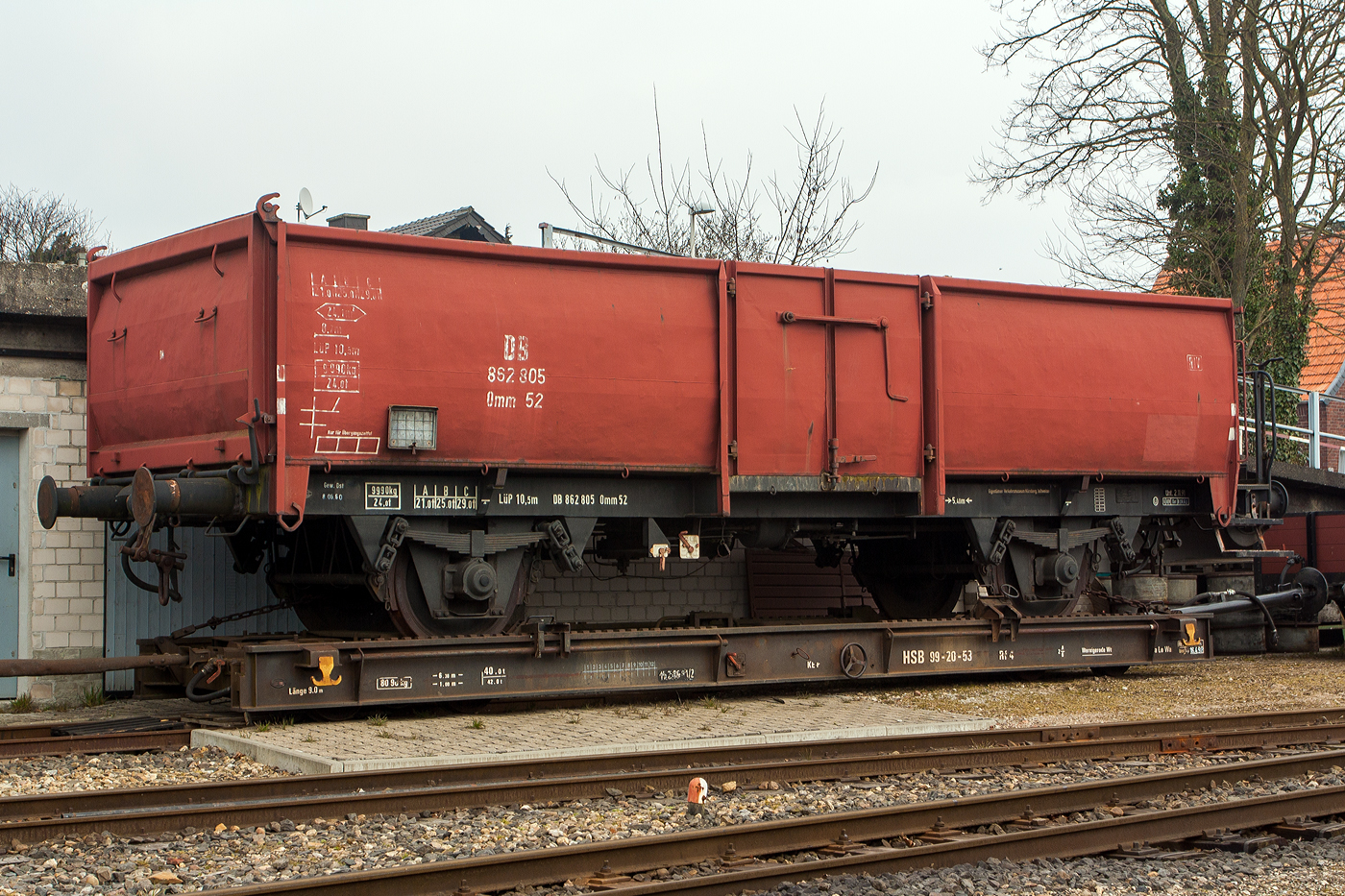Der zweiachsige normalspurige Güterwagen DB 862 805, der Gattung Omm 52, verladen auf dem ex HSB vierachsigen meterspurigen Rollwagen 99-20-53, der Gattung Rf 4, am 31 März 2013 beim Kleinbahnmuseum Selfkantbahn der IHS - Interessengemeinschaft Historischer Schienenverkehr e. V. in Schierwaldenrath.

Normalspuriger Güterwagen:
Der normalspurige Güterwagen DB 862 805 wurde 1958 von der Maschinenfabrik Esslingen unter der Fabriknummer 25125 gebaut und an die Deutsche Bundesbahn geliefert. Seit 2000 ist er bei der Selfkantbahn, der Wagen ist Eigentum DB-Museum Nürnberg (DB AG) und eine Leihgabe an die IHS.

In den 50er Jahren stellten die offenen Güterwagen die größte Gruppe unter den Güterwagen dar. Sie wurden nicht nur zum Transport von Schüttgütern wie Sand, Kies und Kohle sondern auch für Holz, Maschinen und witterungsunempfindlichen Stückgütern eingesetzt. Die Entwicklung des vollständig geschweißten Omm 52 erfolgte hauptsächlich bei der Waggonfabrik Uerdingen, hierbei wurde Neuland betreten. Der Rahmen bestand nicht mehr wie gehabt aus Walzprofilen, sondern aus Blechen, die so zusammengeschweißt wurden, dass sie Hohlträger bilden. Die Seitenwände erhielten zwischen den Türsäulen und den Ecksäulen keine weiteren Wagenkastensäulen mehr. Sie bestehen nur aus einem abgekanteten Blech. Durch die starke Beanspruchung der Waggons wurde dieses mit der Zeit leicht nach außen gewölbt, so dass die Wände ausgebaucht wirken. Als Stirnwände wurden durch Daumenwellen gesicherte Kopfklappen eingebaut. Lediglich bei Wagen mit Handbremse wurde an der Bremserbühne eine feste Stirnwand (wie hier) eingebaut. So konnte hier nur die linke Stirnwand geöffnet werden. Von 1952 bis 1962 wurden insgesamt 14.919 Exemplare gebaut, die letzten Exemplare wurden bis 1986 genutzt.

Die Wagen laufen auf rollengelagerten Radsätzen der Bauart 88 mit gewalzten Vollrädern. Die Federung übernehmen achtlagige, 1.200 mm lange Blattfedern mit einem Querschnitt von 120 mm x 16 mm, auf die sich der Wagen über Doppelschakengehänge abstützt. Die Wagen ab 1954 sind mit einer Knorr Bremse (KE-G) ausgestattet.

Die Wagen haben eine durchgehende Zugeinrichtung mit normalem Zughaken und Schraubenkupplung. Es sind Ringfeder-Hülsenpuffer mit einer Endkraft von 350 kN montiert. Das Untergestell ist diagonalelastisch, ohne Diagonalstreben und aus Stahl der Güte St 52 hergestellt. Es besteht aus dicht verschweißten Hohlprofilen, die aus abgekanteten 5 bis 8 mm starken Blechen bestehen. An den Ecken sind Verstärkungen eingebaut. Dimensioniert ist das Untergestell für eine Achslast von 20 t und für einen Pufferdruck von 240 t. Einige Wagen besitzen einen um 500 mm verlängerten Rahmen über dem sich eine Bremserbühne befindet.Der Bremserstand ist mittels Schrauben an einem Kopfstück befestigt.

Die Seitenwände bestehen aus 3 mm dicken, auf der ganzen Länge nach außen profilierten Blechen und Hohlprofilen. Die Stirnwände sind als Kopfklappen ausgeführt, bestehen aus 4 mm dickem Stahlblech und sind ebenfalls nach außen profiliert. Aufgrund dieser Konstruktion konnte auf die sonst üblichen Seitenrungen verzichtet werden. Nur die zur Türaufhängung nötigen Türrungen sind vorhanden. Die zweiflügeligen Ladetüren haben eine Öffnungsweite von 1.800 mm. Aufgrund der fehlenden Seitenrungen neigen die Seitenwände der Wagen stark zum Ausbeulen. Im Laufe der Zeit bildeten sich rundliche Wände, bei denen die Knicke fast völlig verschwunden waren. Der Wagenboden ist zwischen den Langträgern mit 45 mm dicken Kiefernbohlen ausgelegt. Zwischen den Langträgern und den Seitenwänden sind 5 mm dicke Bleche verlegt.

Zu Beginn ihrer Einsatzzeit wurden die Wagen üblicherweise mit Schütt- und Stückgut beladen. Bedingt durch einen Wandel im Güterverkehr hin zu Spezialwagen zeichnete sich schon bald ein Überhang an offenen Wagen ab. Deshalb beschloss die DB, lediglich einen Teil ihrer offenen Wagen für einen längerfristigen Weiterbetrieb zu erhalten. Der Rest der Wagen bekam nur noch Bedarfsuntersuchungen und schied bald aus dem Betriebsdienst aus. Auch ein Teil der E 037 war davon betroffen.

TECHNISCHE DATEN:
Spurweite: 1.435 mm (Normalspur)
Gattung: Omm 52 (ab 1965 E037, Gattungszahl 5044)
Länge über Puffer: 10.500 mm
Achsabstand: 5.400 mm
Länge der Ladefläche: 8.700 mm
Ladefläche: 24,1 m²
Eigengewicht: 9.990 kg
Max. Ladegewicht: 29 t ab Streckenklasse C

Der Schmalspur Rollwagen 99-20-53:
Der vierachsige 1.000 mm Rollwagen der Gattung Rf 4 wurde 1964 vom (RAW) Reichsbahnausbesserungswerk Jena, als DR 99-20-53 gebaut (andere Quellen schreiben 1959 vom VEB Waggonbau Niesky). Am 1. Februar 1993 übernahm die HSB mit Sitz in Wernigerode von der Deutschen Reichsbahn (DR) Anlagen, Fahrzeuge, Personal und fungiert seitdem als Eisenbahnverkehrs- (EVU) und Eisenbahninfrastrukturunternehmen (EIU), so wurde auch dieser Rollwagen zum HSB 99-20-53 Rf 4, 1999 wurde er an die IHS verkauft und dort abgestellt, eine Inbetriebnahme ist für möglichst bald vorgesehen.

Auf den Schmalspurbahnen der ehemaligen DDR erfolgte der Güterverkehr fast ausschließlich mittels Rollwagen, auf denen regelspurige Güterwagen transportiert wurden. Mit der Wende/Wiedervereinigung und den Betriebsschließungen der folgenden Jahre schmolz das Güterverkehrsaufkommen auf einen Bruchteil. 

TECHNISCHE DATEN:
Spurweite: 1.000 mm (Meterspur)
Gattung: Rf 4
Länge über Puffer: 9.000 mm
Drehzapfenabstand: 6.300 mm
Achsabstand im Drehgestell: 1.000 mm
Länge der Ladefläche: 8.700 mm
Eigengewicht: 8.090 kg
Max. Ladegewicht: 40 t 
Bremsausrüstung: bodenbedienbare Handbremse und Druckluftbremse
