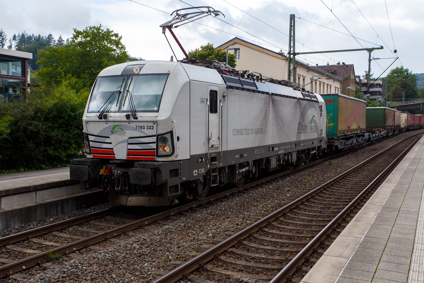 Die TXL eigene SIEMENS Vectron der TX Logistik AG, bisher hatte diese nur Loks angemietet. Die recht neue weiße TXL 7193 322 „Connected to Nature“ (91 80 7193 322-3 D-TXL) der TXL - TX Logistik AG (Troisdorf) fährt am 28 Juli 2025, mit einem KLV-Zug, durch den Bahnhof Kirchen (Sieg) in Richtung Betzdorf bzw. Köln.

Die SIEMENS Vectron MS (X4E) wurde 2024 von Siemens Mobility in München-Allach unter der Fabriknummer 23680 gebaut und am 31.03.2025 an die TXL ausgeliefert. Die mit 6.400 kW konzipierte Mehrsystemlok ist in der Variante A09-4f ausgeführt und hat so die und hat so die Zulassungen und entspr. Länderpakete für Deutschland, Österreich uns Italien (D / A / I).

Über TX Logistik AG
TX Logistik wurde 1999 als privates Eisenbahnverkehrsunternehmen gegründet und bietet mit Verbindungen in elf Ländern ein leistungsfähiges europäisches Netzwerk. Das Unternehmen verfügt über Tochtergesellschaften in der Schweiz, Österreich, Dänemark und Schweden sowie eine lokale Präsenz in Italien. In den Geschäftsbereichen Intermodal und Rail Freight entwickelt TX Logistik umfassende Schienenlösungen für kontinentale und maritime Verkehre sowie maßgeschneiderte Konzepte für konventionelle Fracht. Mit 650 Mitarbeitern und 8,6 Milliarden gefahrenen Tonnenkilometern erwirtschaftete das Unternehmen 2021 einen Jahresumsatz von 253 Millionen Euro. Seit Januar 2017 gehört TX Logistik zu 100 Prozent der Mercitalia Logistics S.p.A., einer Tochtergesellschaft der FS - Ferrovie dello Stato Italiane. Mittlerweile gehört das Unternehmen mit zu den Größten für den Schienengüterverkehr in Europa.

Das Unternehmen bietet den ganzen Umfang an Schienengüterverkehr, inklusive Containertransport und kombiniertem Verkehr an. Wichtigste Transportstrecken sind von den Häfen Hamburg, Bremerhaven, Rotterdam und Antwerpen nach Süddeutschland, Schweiz, Österreich und Italien.

TX Logistik setzt nun auf eigene Vectron Loks:
Anfang Oktober 2024 hat die TX Logistik AG ersten drei von 40 modernen Vectron-Lokomotiven des Herstellers Siemens Mobility aufs Gleis gesetzt, die das zur Mercitalia Logistics (FS Italiane Group) gehörende Schienenlogistikunternehmen im Mai 2023 bestellt hatte. Die Erweiterung der Fahrzeugflotte ist für TX Logistik eine wichtige Voraussetzung, um im intermodalen und grenzüberschreitenden Schienengüterverkehr weiter zu wachsen. Die neuen Lokomotiven werden vor allem auf dem Brenner- und dem Schweiz-Korridor eingesetzt, den strategisch wichtigen Nord-Süd-Achsen in Europa.

Beide Korridore sind stark frequentiert und stellen hohe Anforderungen an die eingesetzten Lokomotiven – von der Zugkraft über die Stabilität bis hin zur grenzüberschreitenden Systemkompatibilität. TX Logistik hat dazu die Maschinen mit verschiedenen Länderpaketen bestellt. 20 Vectron erhalten das Länderpaket für den Betrieb in Deutschland, Österreich, Schweiz, Italien und den Niederlanden (D-A-CH-I-NL) und sollen bis Anfang 2025 übergeben werden. Die Auslieferung der 20 Lokomotiven mit der Ausstattung für den deutsch-österreichisch-italienischen Korridor (D-A-I) soll bis zum Jahresende 2025 erfolgen.

Die Entscheidung für den Kauf der Vectron-Lokomotiven unterstreicht zugleich das Bestreben von TXLogistik, Schienengüterverkehre als umweltfreundliche und effiziente Alternative zum Straßentransport weiter voranzutreiben. Um dies zu unterstreichen und gleichzeitig für den Einstieg in den intermodalen Transport zu werben, hat die erste der drei Vectrons, die im Zughotel in Braunschweig übergeben wurden, eine spezielle Lok-Beklebung mit dem Schriftzug „Start now (Nature). Driven by Green Passion“ erhalten.

Die neuen Loks bieten mit ihrer Flexibilität und Leistungsfähigkeit ideale technische Voraussetzungen, um den steigenden Anforderungen des europäischen Güterverkehrs gerecht zu werden. Mit der modernen Vectron-Flotte, so TX Logistik, sei man mittelfristig nun in der Lage, die Kapazitäten auf dem Brenner- und dem Schweiz-Korridor deutlich zu erhöhen sowie die Effizienz und Zuverlässigkeit im Schienengüterverkehr weiter zu verbessern.