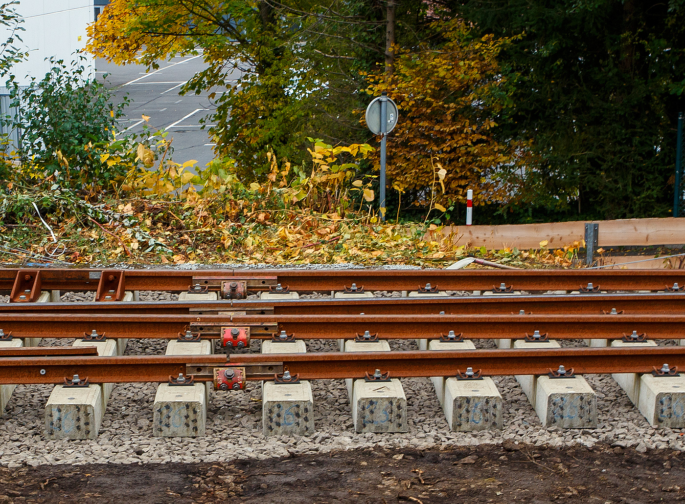 Die Weichen 25 und 26 beim Bahnhof Herdorf sind beide am 12 Oktober 2025 eingebaut, müssen noch eingeschottert werden. Hier sieht man im Bauzustand die provisorisch gelaschten Schienenstöße, zwischen 2 Segmenten der Weichen 26. Die einzelnen Schienenstöße bestehen jeweils aus 2 formschlüssigen Laschen und einer Robel ROCLAMP 68.05 „lang“ Klemme (langer Notlaschenverbinder). Es ist eine formschlüssige und sicheren Verbindung, die je nach Infrastrukturbetreiber bis zu 200 km/h zugelassen sind. 