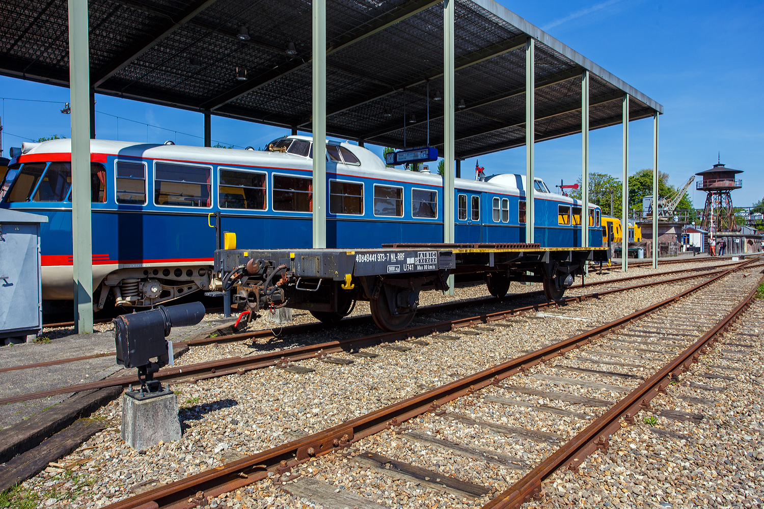 Hier ein weiterer zweiachsiger Kupplungswagen (Koppelwagen) ex 40 84 9441 973-7 NL-RFF (Rotterdam Rail Feeding), ex NS 01 84 1272 371-2, ex NS 7792, der Gattung U741, am 29 April 2025 im Het Spoorwegmuseum (bis 2005 NSM - Nederlands Spoorwegmuseum / Niederlndischen Eisenbahnmuseum) in Utrecht im ehemaligen Bahnhof Maliebaan. Dahinter steht “De Kameel“ (das Kamel) NS 20 (DE1 – 20). 

Diese Adapter- oder Kupplungswagen sind ntig, wenn man mit einer Lok mit Puffern und Schraubkupplung Triebwagen und -zge mit Scharfenberger-Kupplung rangieren oder abschleppen muss. 

Nach dem Umbau (ca. 1960) aus Flachwagen erhielt der Wagen an erst an beiden Wagenenden eine Scharfenberger-Kupplung. Auf der Ladeflche 
des Fahrgestells wurden auerdem quer 15 Stahlschienen fr zustzlichen Ballast angebracht. An zwei Ecken wurden Rangiertritte angebracht. 

Die Kupplungshhe betrgt fest 610 mm ber Schienenoberkante und ist nicht wie bei anderen hhenverstellbar, somit knnen nur Triebzge der Typen mat'46, mat'54, DE 1, DE 2 und DE 3 gekuppelt werden. Aufgrund fehlender Luftanschlsse an der Scharfenberger-Kupplung ist diese Kupplung ausschlielich mechanisch. Aber z.B. die Rangierloks der Serien 100, 200 und 300 (Orsik und Sik) haben eh keine Druckluftbremse. Der Wagen war beim Wph Amersfoort stationiert.

Spter wurde die Scharfenberger-Kupplung an einem Wagenende wieder entfernt und erhielt dort wieder Puffern und Schraubkupplung.

2004 ging der Wagen ber die RFF an das Eisenbahnmuseum, wo er heute ausschlielich auf der Utrechter Maliebaan eingesetzt wird.

TECHNISCHE DATEN:
Spurweite: 1.435 mm (Normalspur)
Anzahl der Achsen: 2
Lnge ber Puffer: 10.580 mm
Achsabstand: 6.000 mm
Ladeflche: 
Leergewicht: 9.000 kg
Max. Zuladung: 0 kg (Nur als Kupplungswagen verwendbar)
Hchstgeschwindigkeit: 80 km/h
