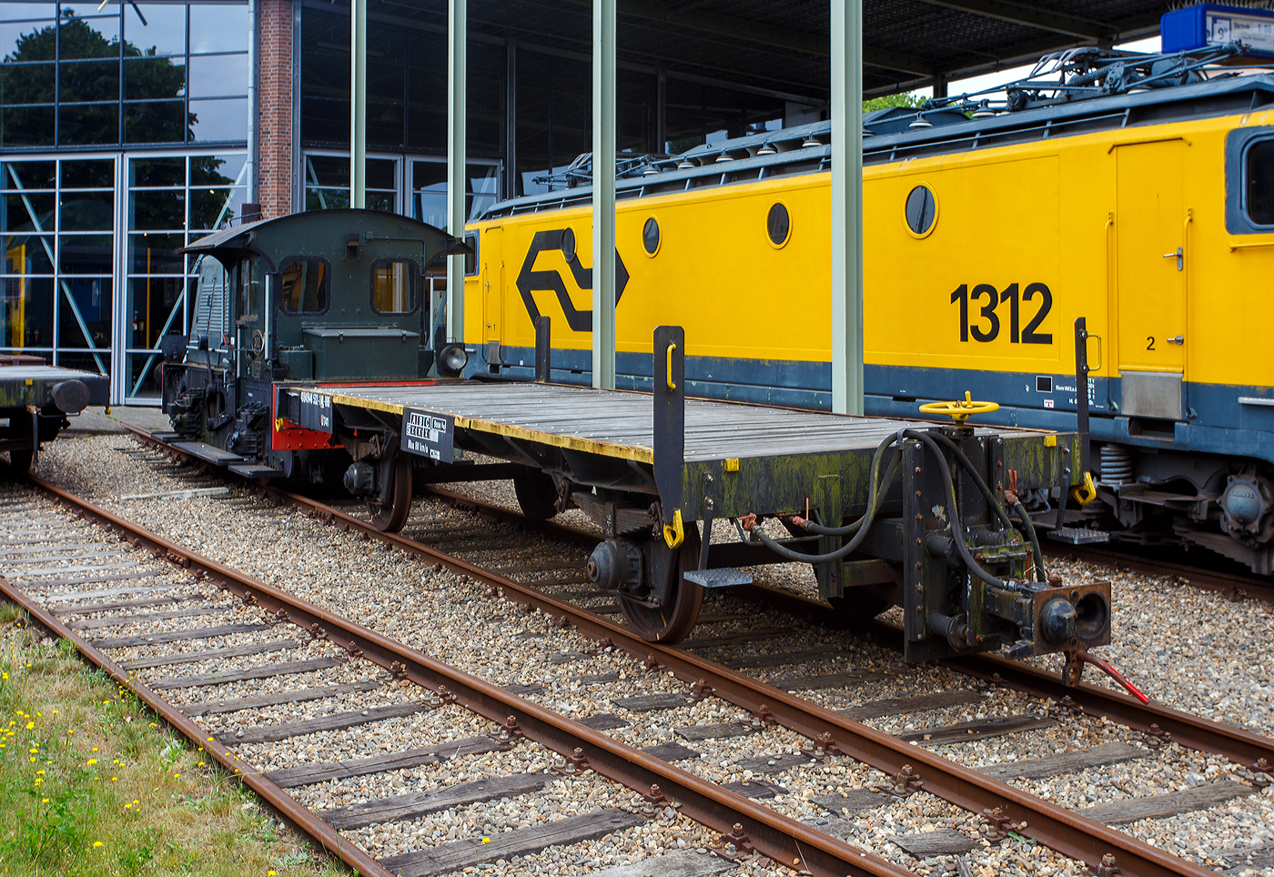 Hinter der ex NS Sik 311 der zweiachsige Kupplungswagen (Koppelwagen) ex 40 84 9441 532-1 NL-RFF (Rotterdam Rail Feeding), ex 30 84 9820 501-9 NL-NS, ex NS 61844, der Gattung U741, am 24 Juni 2025 im Het Spoorwegmuseum (bis 2005 NSM - Nederlands Spoorwegmuseum / Niederlndischen Eisenbahnmuseum) in Utrecht im ehemaligen Bahnhof Maliebaan. 

Diese Adapter- oder Kupplungswagen sind ntig, wenn man mit einer Lok mit Puffern und Schraubkupplung Triebwagen und -zge mit Scharfenberger-Kupplung rangieren oder abschleppen muss. 

Nach dem Umbau (ca. 1970) aus Flachwagen erhielt der Wagen an einem Wagenende eine hhenverstellbaren Scharfenberger-Kupplung und wurde in Hoek van Holland stationiert. Die Kupplungshhe ist von 610 mm ber Schienenoberkante bis 1.070 mm verstellbar, sodass er an alle Stromlinienfahrzeuge gekoppelt werden kann. Am anderen Wagenende behielt er die Puffer und Schraubkupplung, so kann er an diese Seite an eine Lok gekuppelt werden. An der Unterseite des Fahrgestells sind auerdem lngs 15 Stahlschienen fr zustzlichen Ballast angebracht. An drei Ecken wurden Rangiertritte und Eckpfosten mit Griffen angebracht.

Auffllig ist (nach meiner Sichtung), dass der Wagen keine eigenen Bremsen hat. Er hat aber durchgngige Bremsluftleitungen, so dass die abzuschleppende Triebzge von der Lok mit der erforderlichen Druckluft fr die Bremsen versorgt werden konnten. Wobei hier der Sik 311 (Rangierlok) wohl nicht eine ausreichende Luftmenge liefern kann, da der rein mechanisch gebremst wird und keinen Kompressor besitzt.

TECHNISCHE DATEN:
Spurweite: 1.435 mm (Normalspur)
Anzahl der Achsen: 2
Lnge ber Puffer: 9.550 mm
Achsabstand: 5.000 mm
Ladeflche: 
Leergewicht: 9.000 kg
Max. Zuladung: 0 kg (Nur als Kupplungswagen verwendbar)
Hchstgeschwindigkeit: 80 km/h