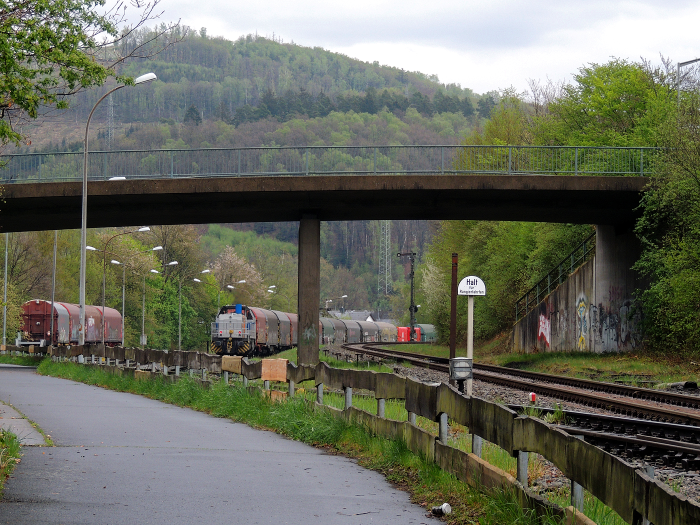 Hochbetrieb in Herdorf am 23 April 2025: 
Durch die vergangenen Osterfeiertage braucht es wohl wieder Nachschub. Die KSW (Kreisbahn Siegen-Wittgenstein) kommt im Sandwich mit einem sehr langen und somit schweren Coilzug, von via Betzdorf/Sieg kommend, und erreicht den KSW-Rangierbahnhof (Betriebsstätte FGE - Freien Grunder Eisenbahn).

Hier am Zugschluss die nachschiebende KSW 47 (92 80 1271 027-5 D-KSW), ex D 2 der HFM, eine Vossloh G 1000 BB, vorne als Zuglok die KSW 44 (92 80 1271 004-4 D-KSW) auch eine MaK G 1000 BB. Im Rbf wird der Zug geteilt, da er für die Weiterfahrt sonst zu lang wäre, und die KSW 44 zieht den ersten Teil weiter zu den Schäfer Werke KG am Pfannenberg in Neunkirchen-Salchendorf. 

Die KSW-Bahnstrecke Herdorf–Pfannenberg-(ehem. Unterwilden) ist eine rund 8 km lange Nebenbahn, bekannt ist sie auch als „Talbahn“. Die Strecke wurde von der 1904 gegründeten Freien Grunder Eisenbahn AG betrieben. Die gebliebenen Gleise und Anlagen sind seit 1970, als Betriebsstätte FGE - Freien Grunder Eisenbahn. Teil der heutigen Kreisbahn Siegen-Wittgenstein.

Später kam dann noch die KSW 43 (92 80 1273 018-2 D-KSW), die asymmetrische Vossloh G 2000 BB, mit einem langen Coilzug von Duisburg an.