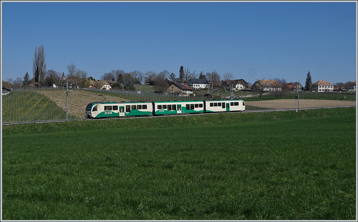 In der sanften Hügellandschaft des Jurasüdfusses bei Vufflens le Château ist ein BAM SURF Be 4/4 - B - Be 4/4 Regionalzug auf dem Weg nach Bière. 

5. April 2023 